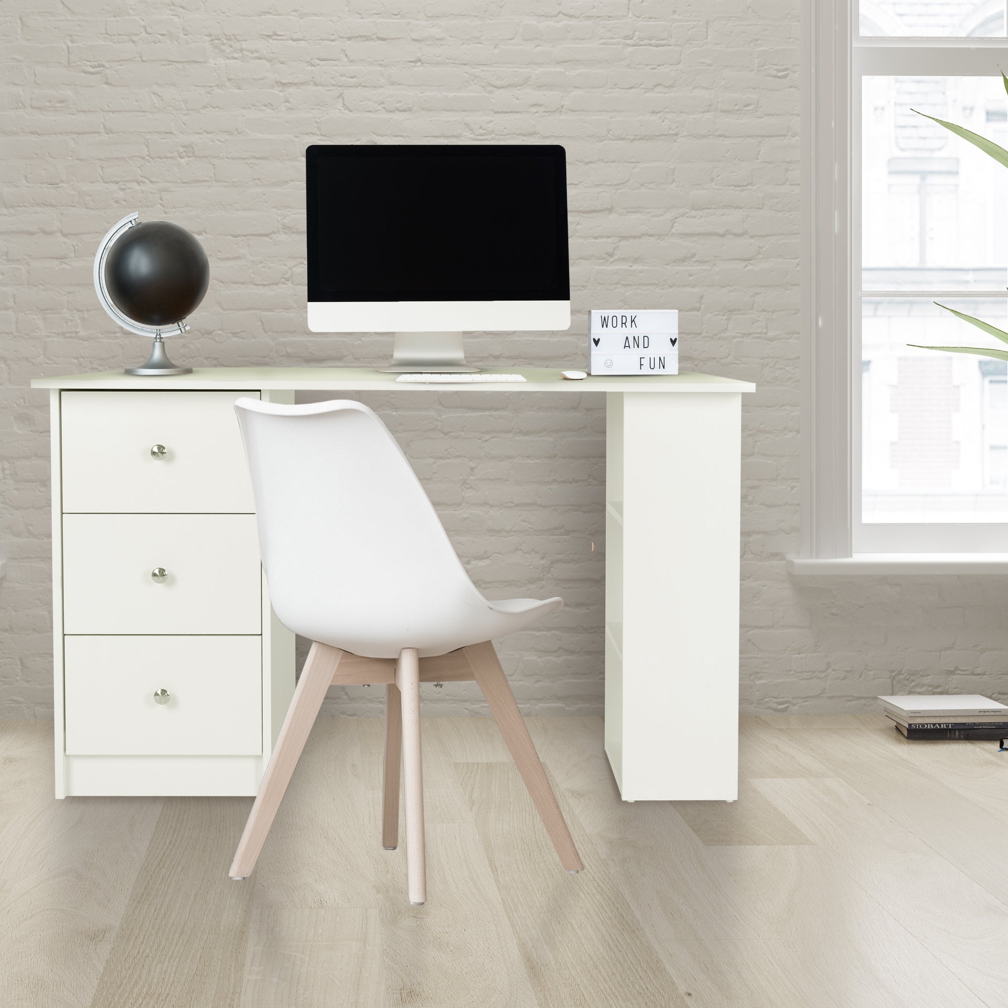 Schreibtisch mit Computer, Stuhl und Globus in einem hellen Raum.