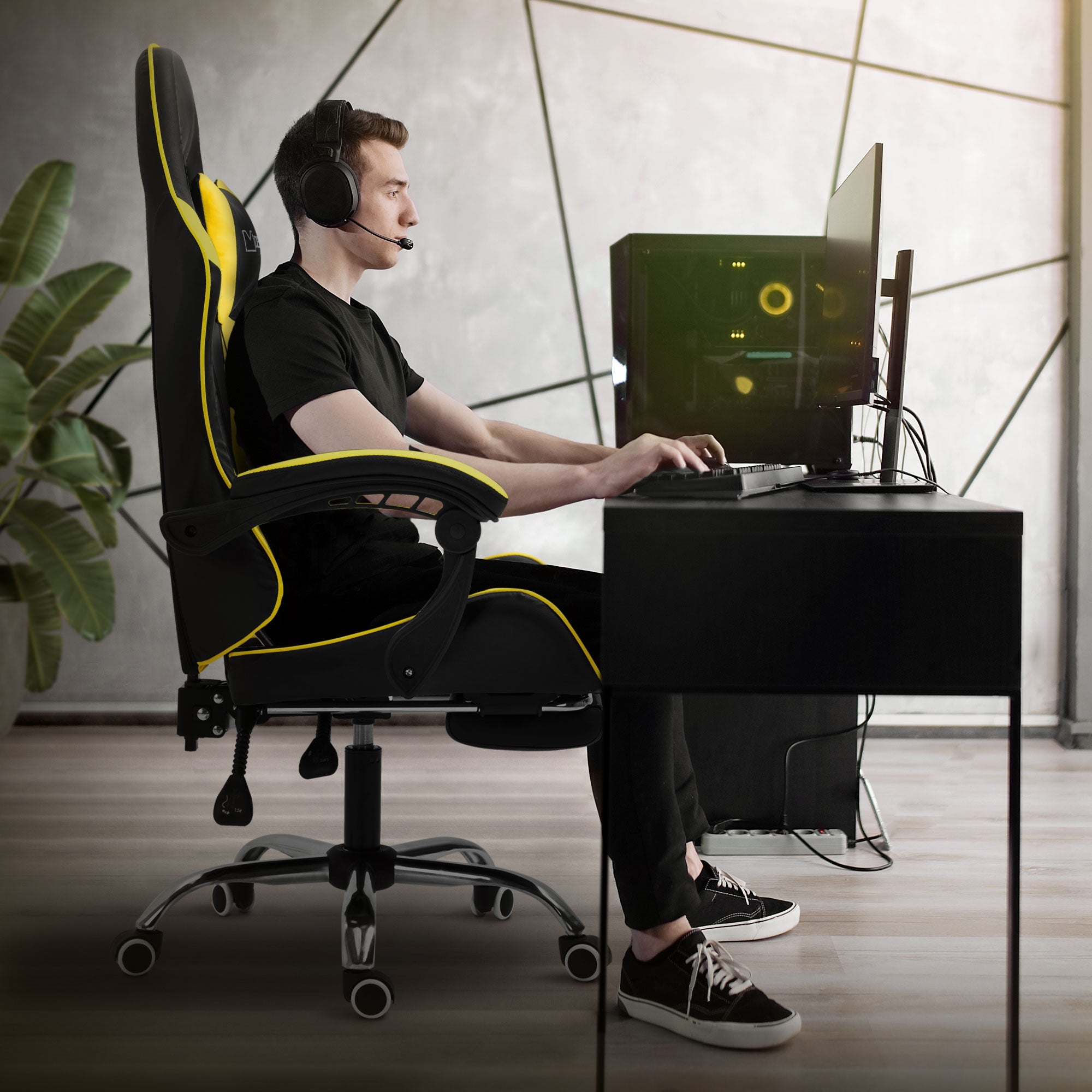 Junger Mann in einem Gamingstuhl, spielt am Computer mit Headset.