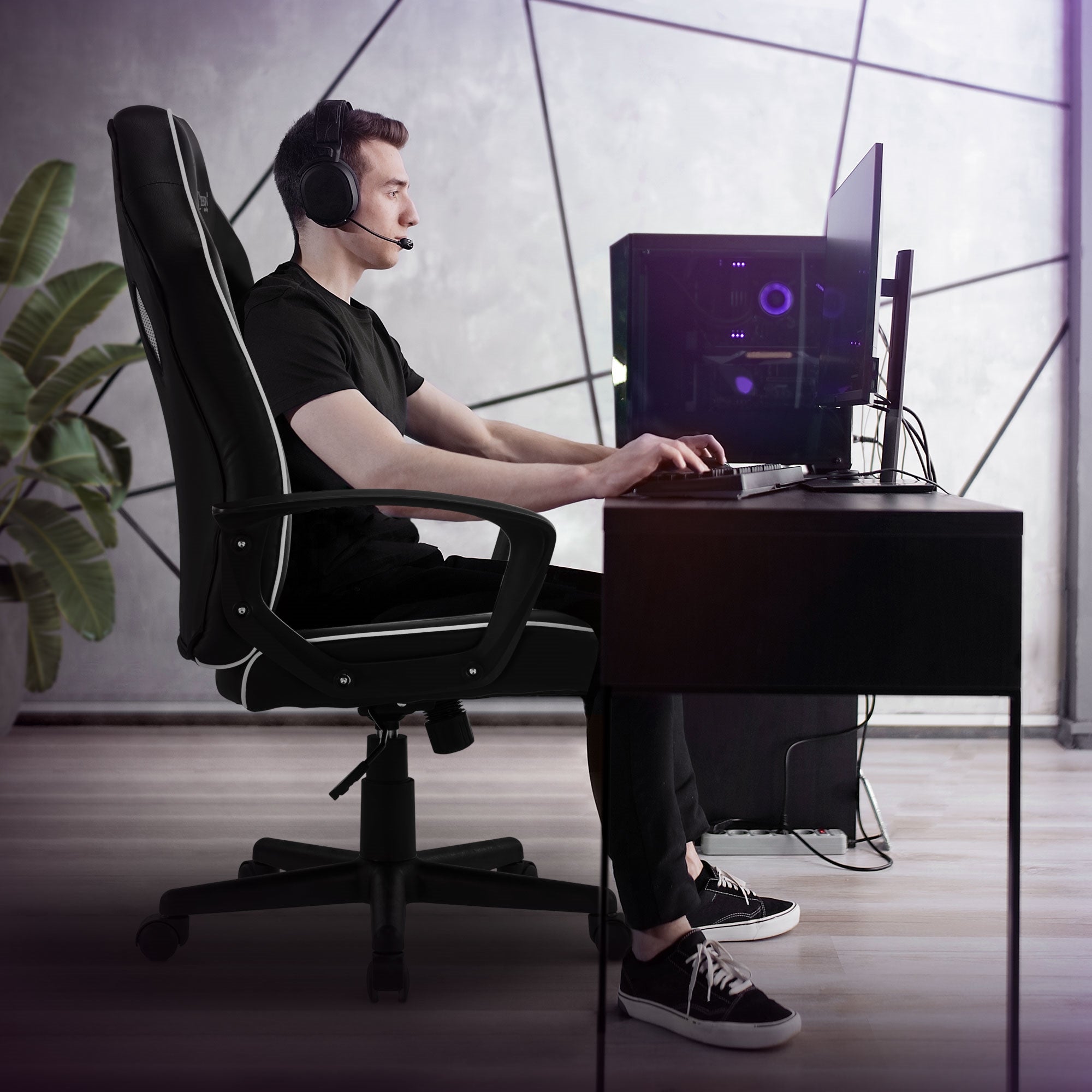 Homme assis à un bureau avec un casque et un ordinateur, entouré de plantes.