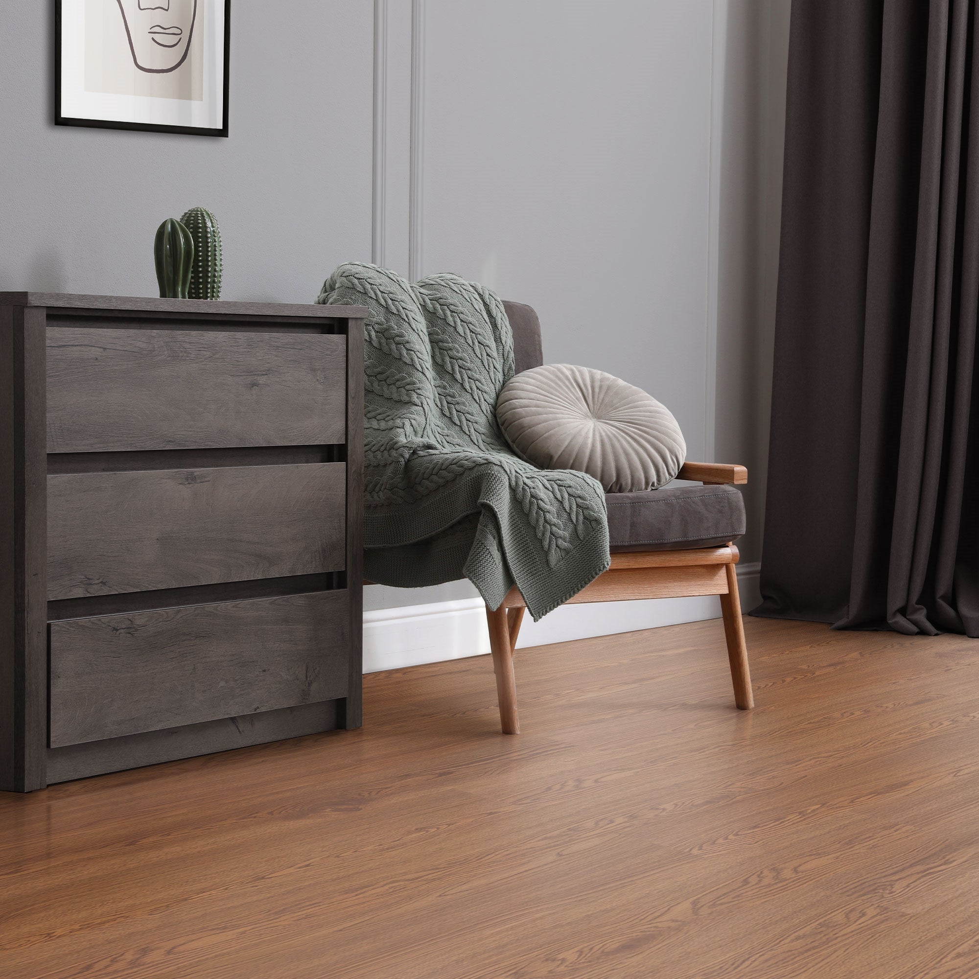 Ein gemütlicher Raum mit einem Sessel, einer Decke und einem Holzfußboden.