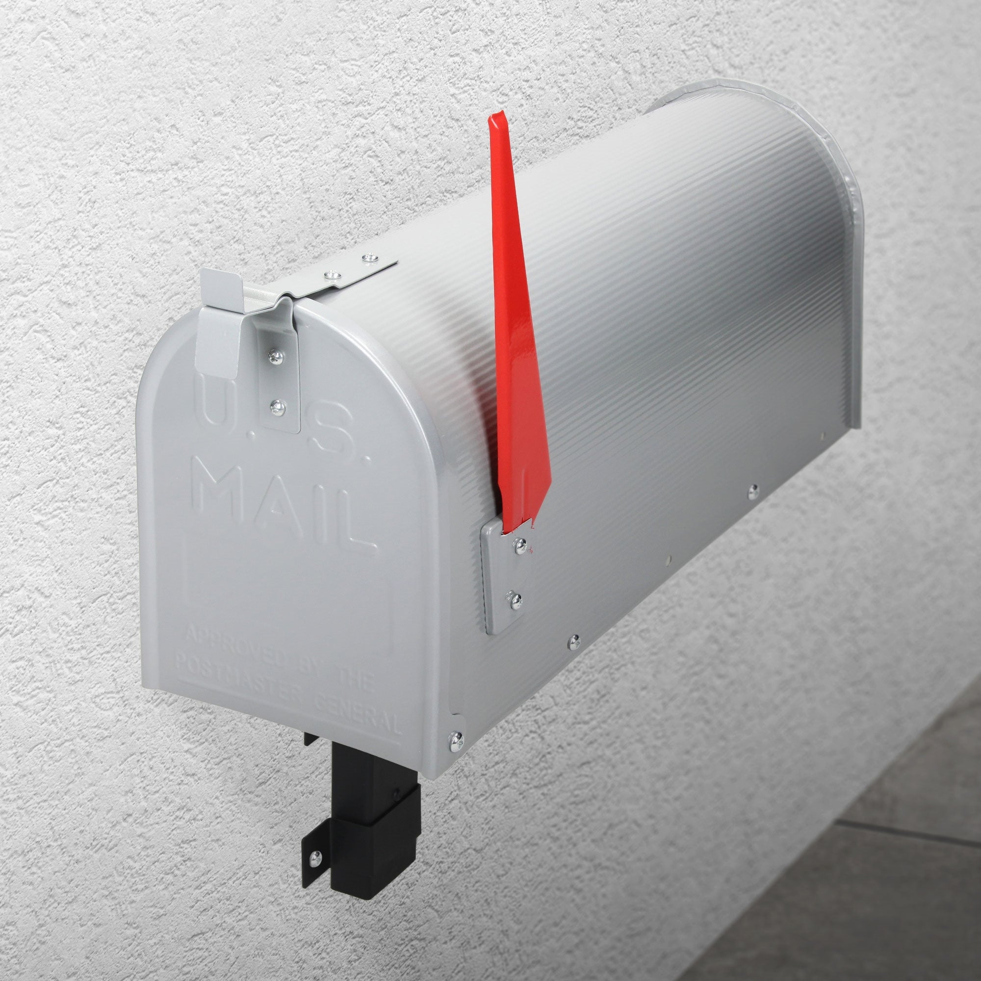 Ezüst postaláda a falon piros zászlókarommal.