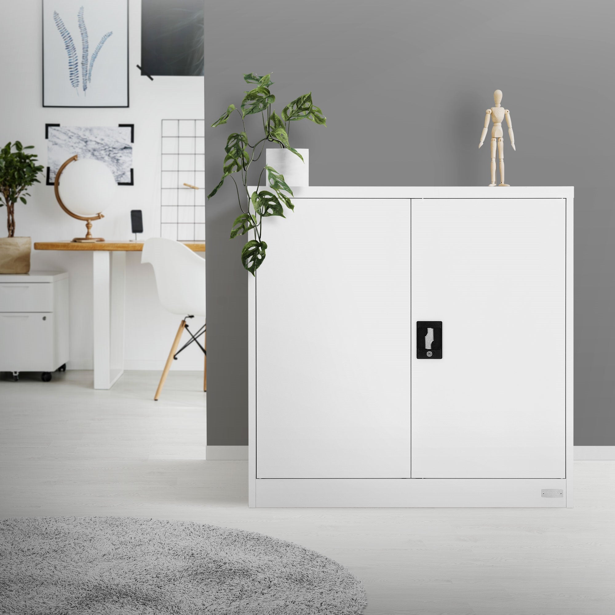 Witte kast met gesloten deuren, daarnaast een plant en een houten figuur.