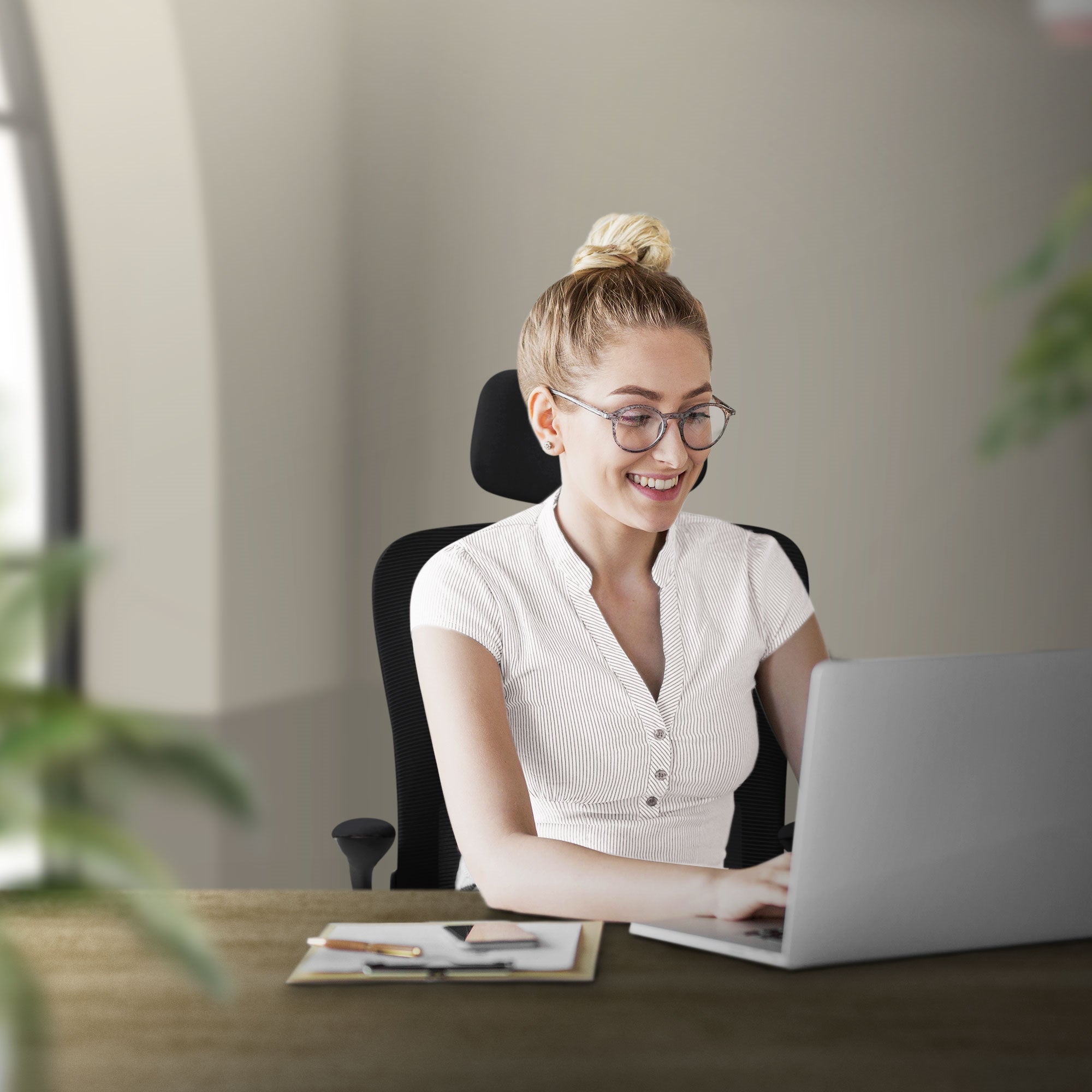 Jonge vrouw zit glimlachend aan een bureau met laptop.
