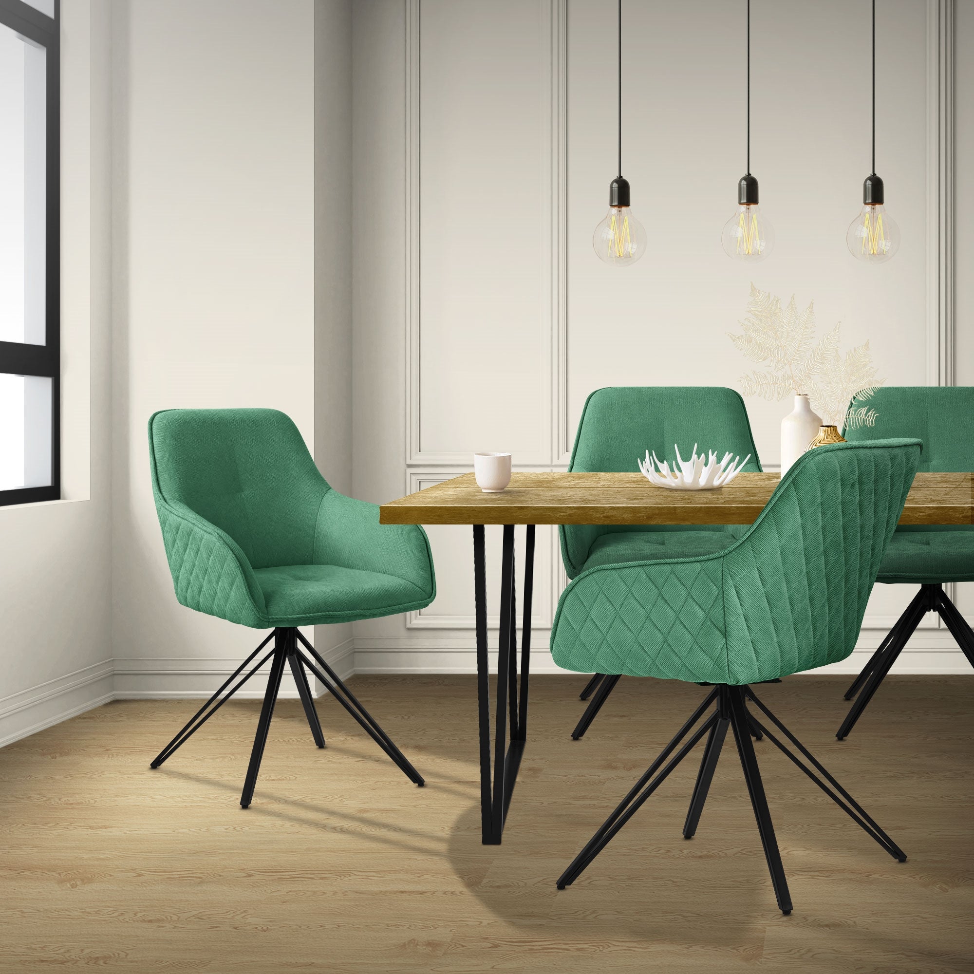 Un comedor con una mesa de madera y sillas verdes, iluminado por lámparas colgantes.