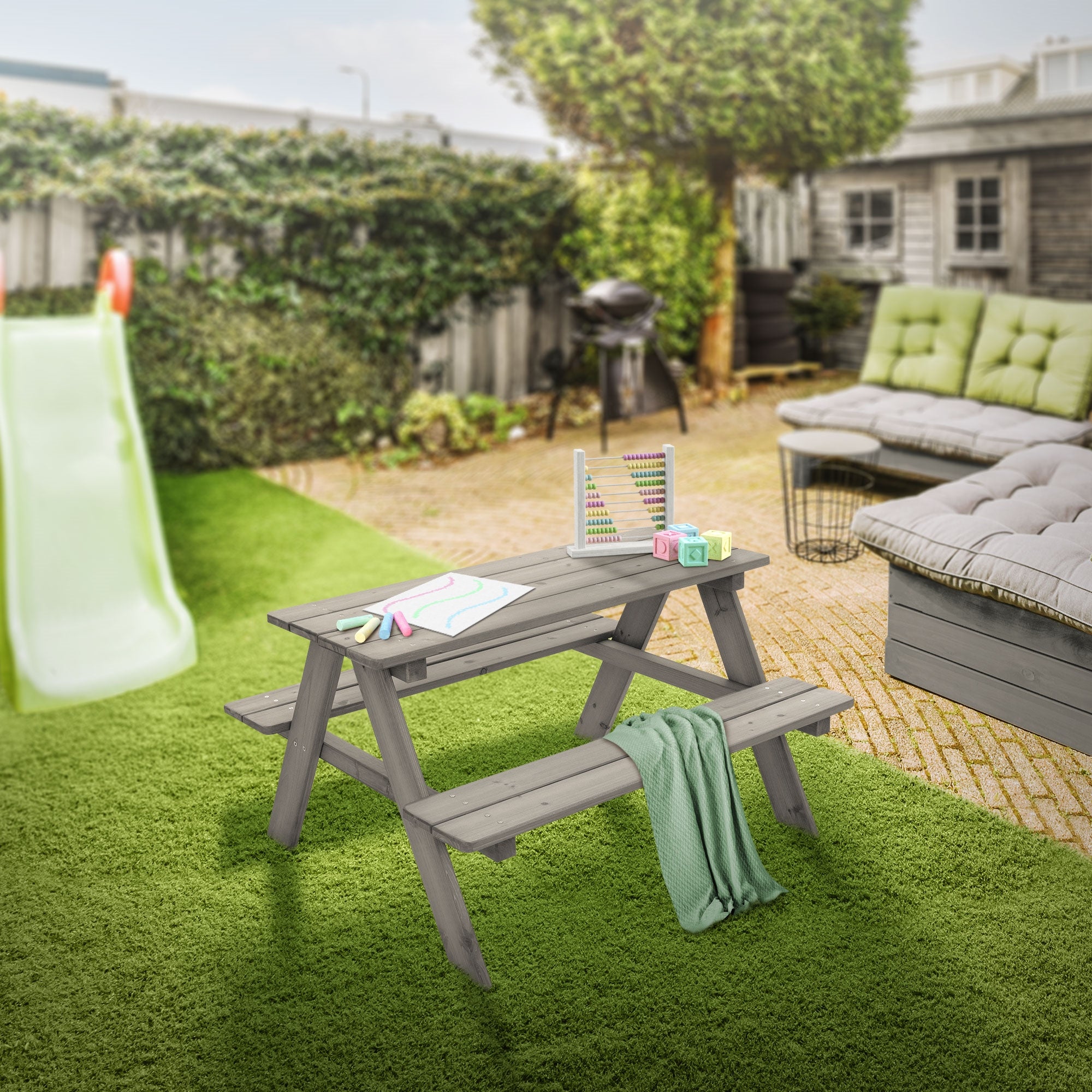 A children's table in the garden, decorated with toys and a blanket.