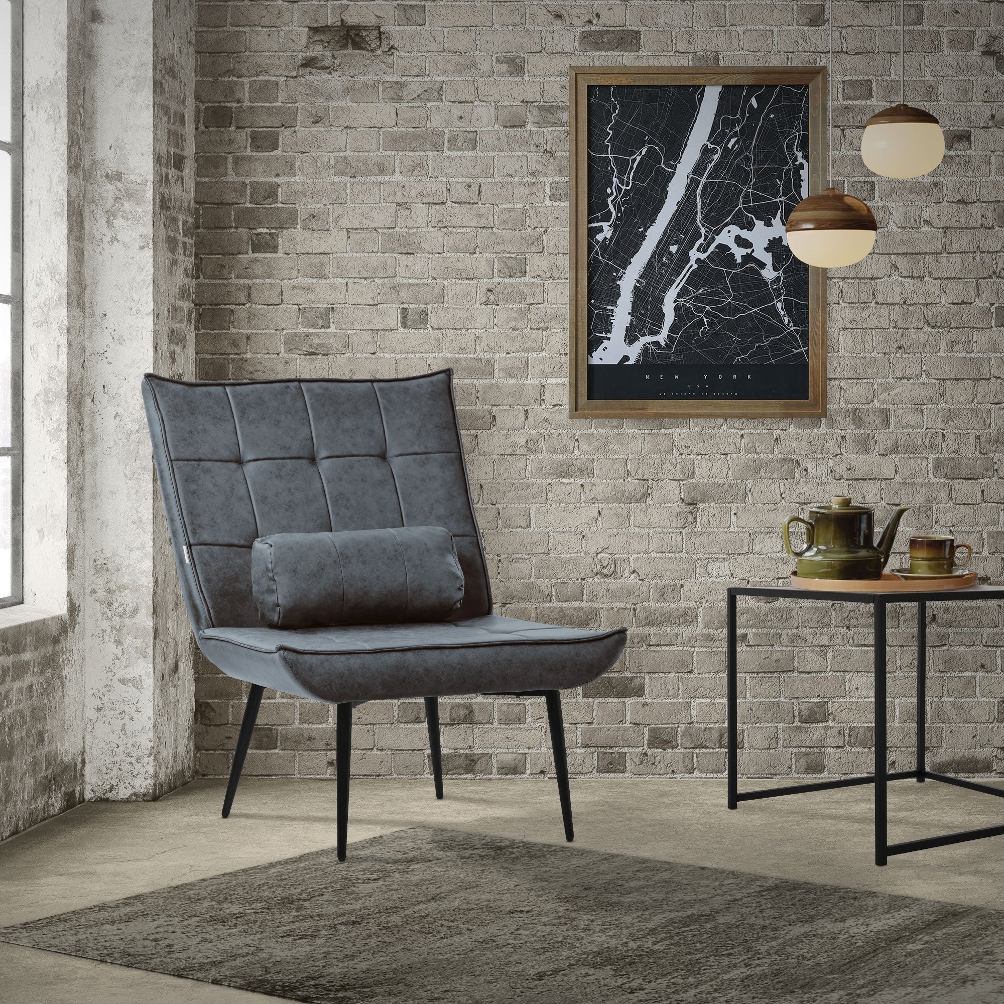 Ein grauer Sessel mit Kissen vor einer Backsteinwand und einem Wandbild.