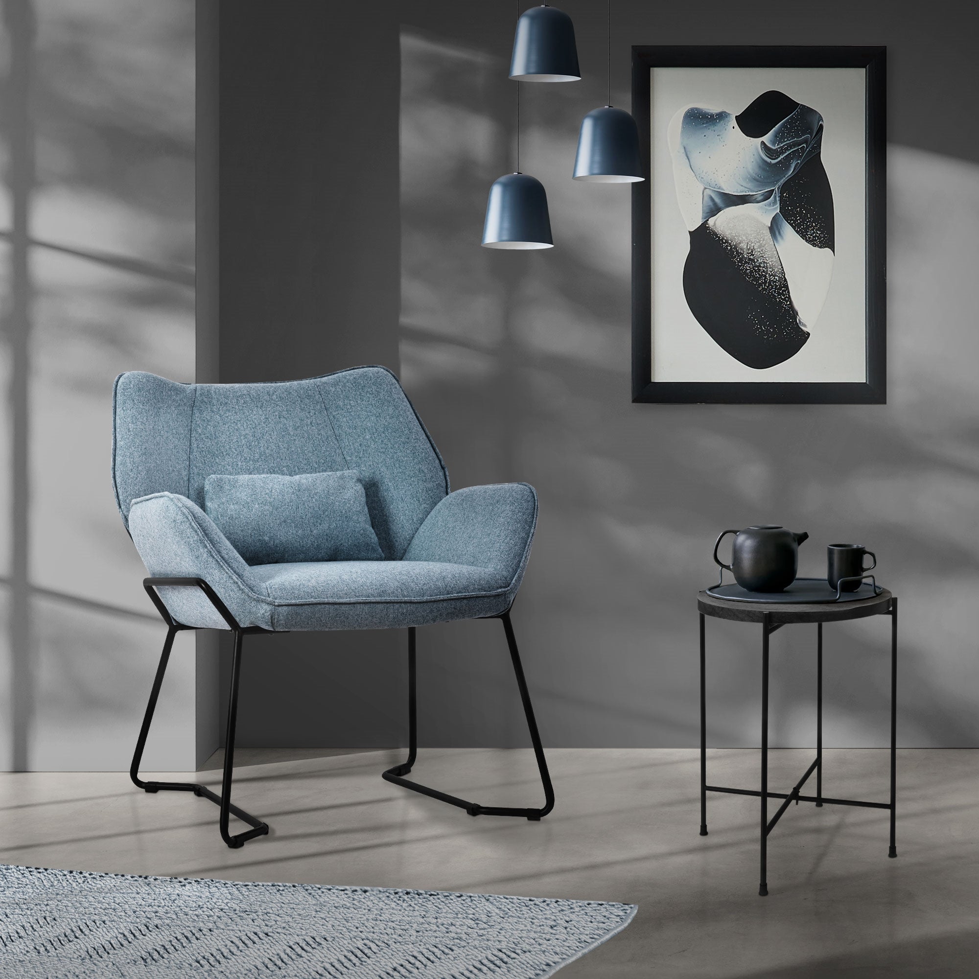 Sillón azul en una habitación con obra de arte y mesa.