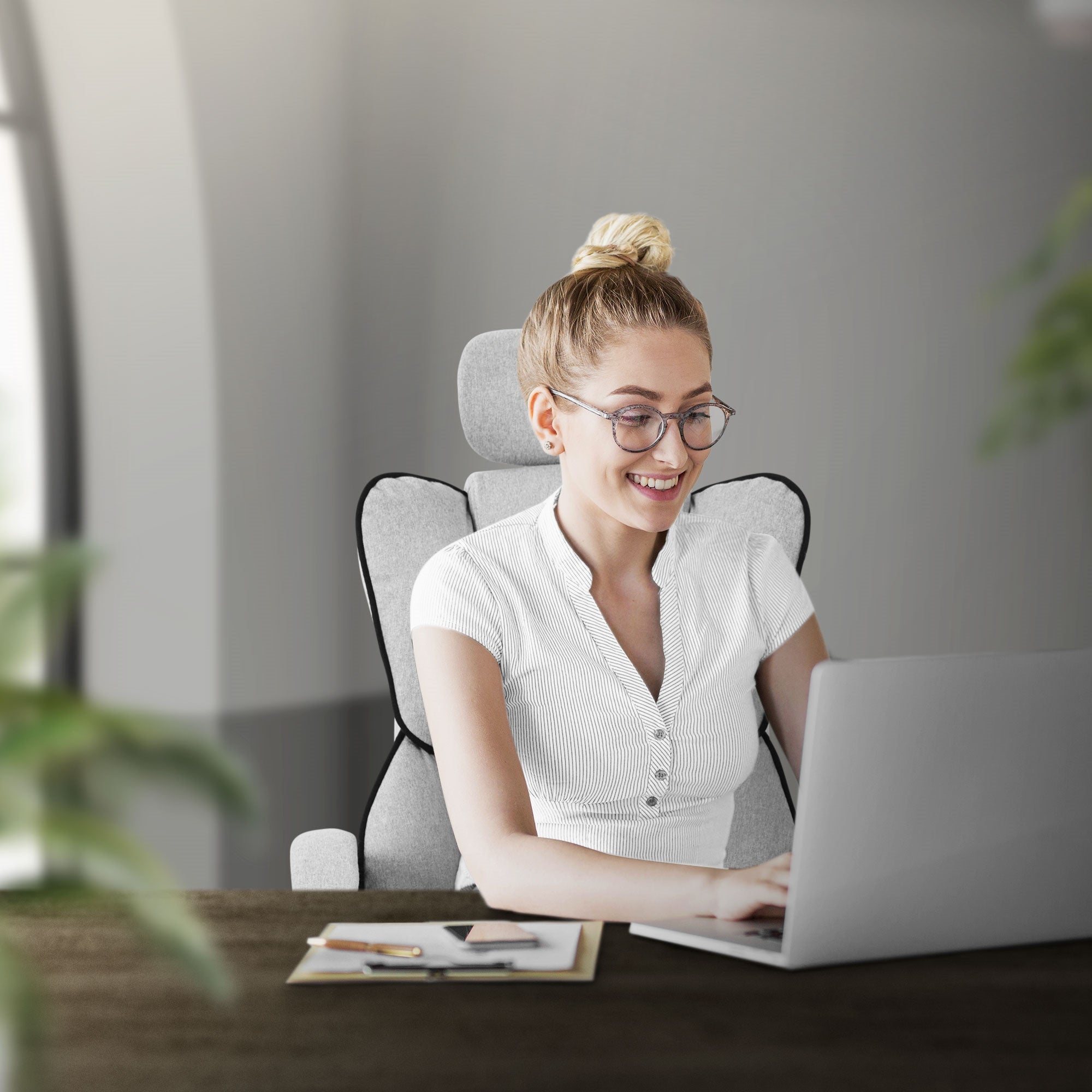 Femme avec des lunettes assise à une table et travaillant sur un ordinateur portable.