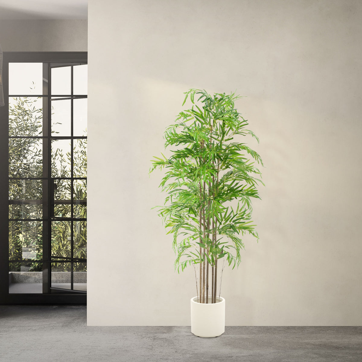 Künstlicher Baum in einem weißen Topf vor einem Fenster.