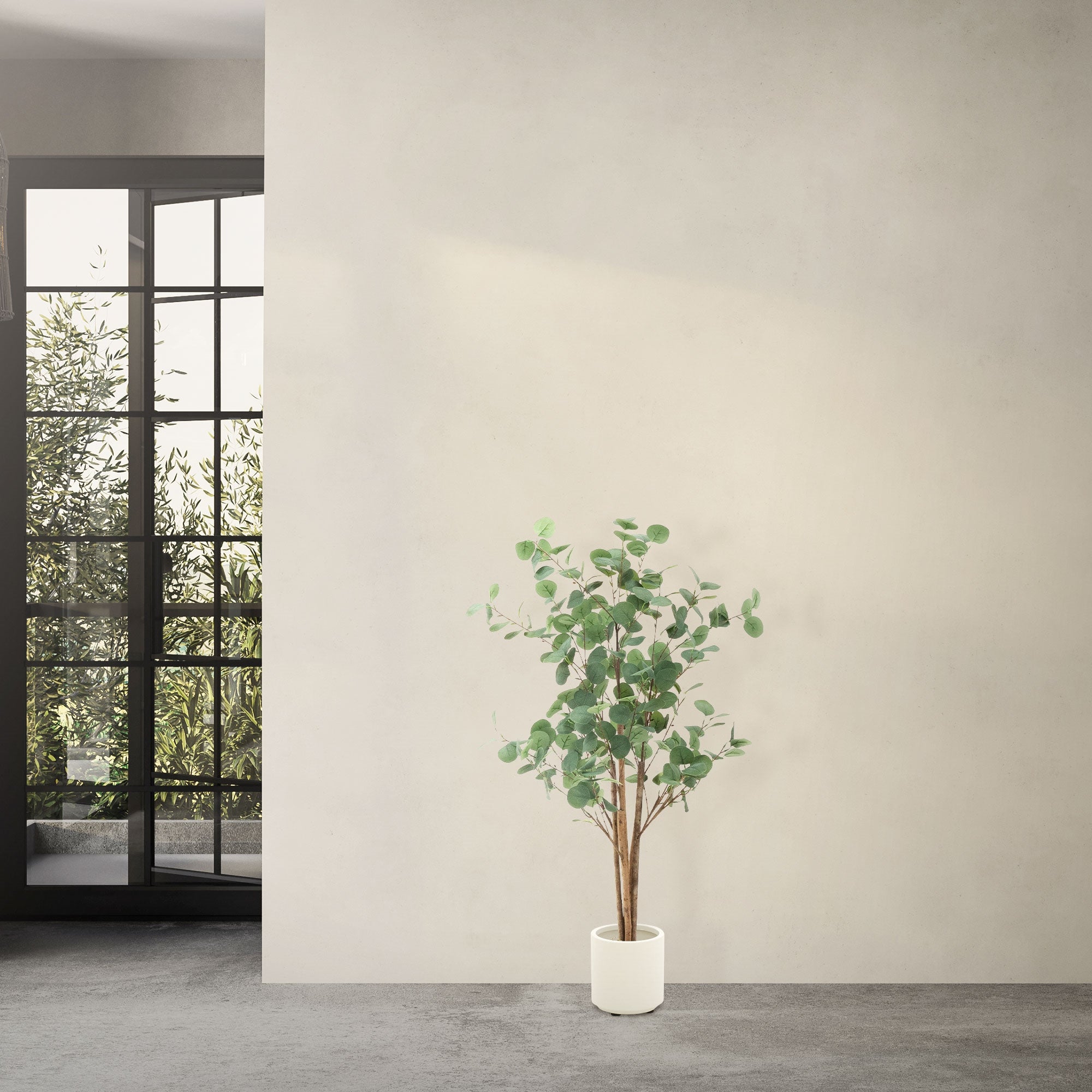 Kunstpflanze Eukalyptus in einem weißen Topf, vor einer hellen Wand und Fenstern.