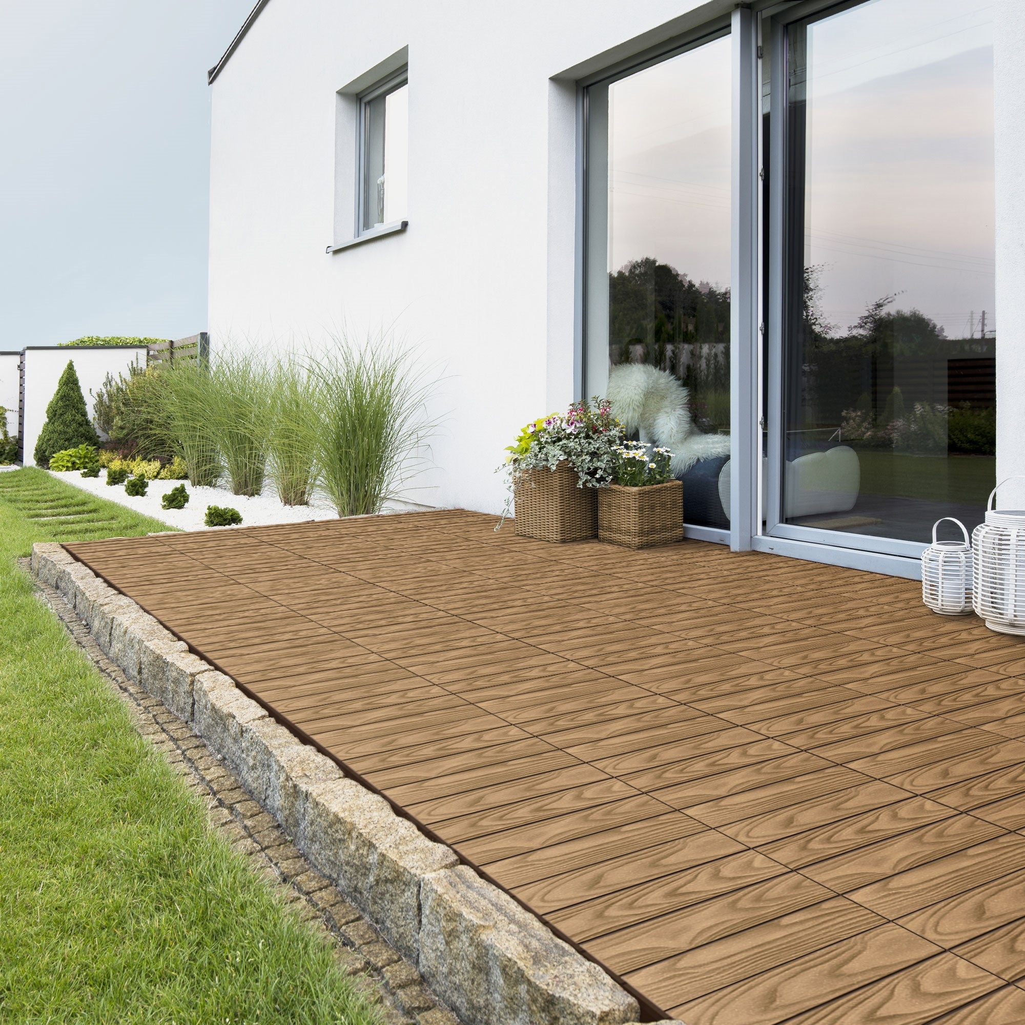 Terras met houtlook-tegels, planten en een glazen wand.