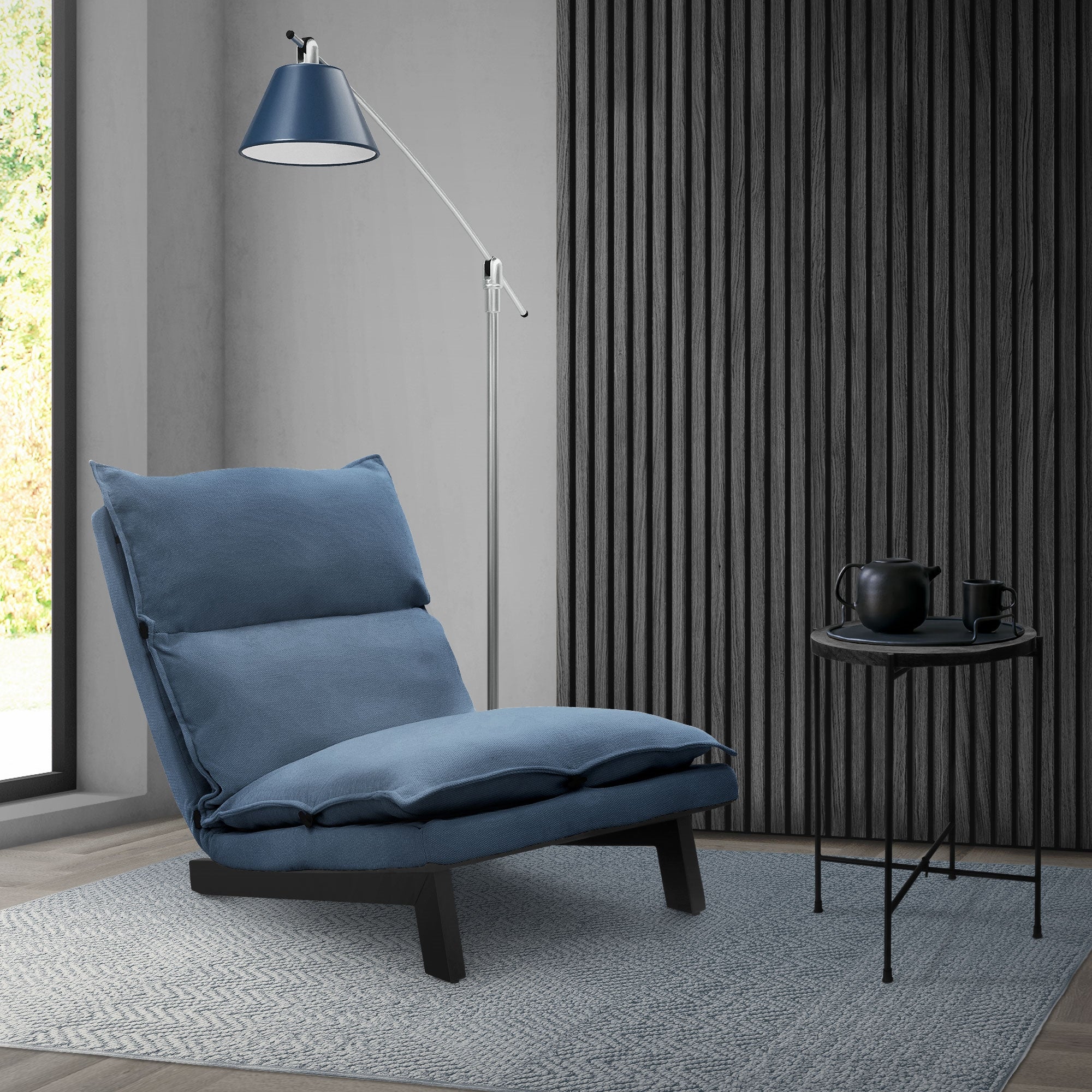 Blauwe stoel naast een vloerlamp en een kleine tafel.