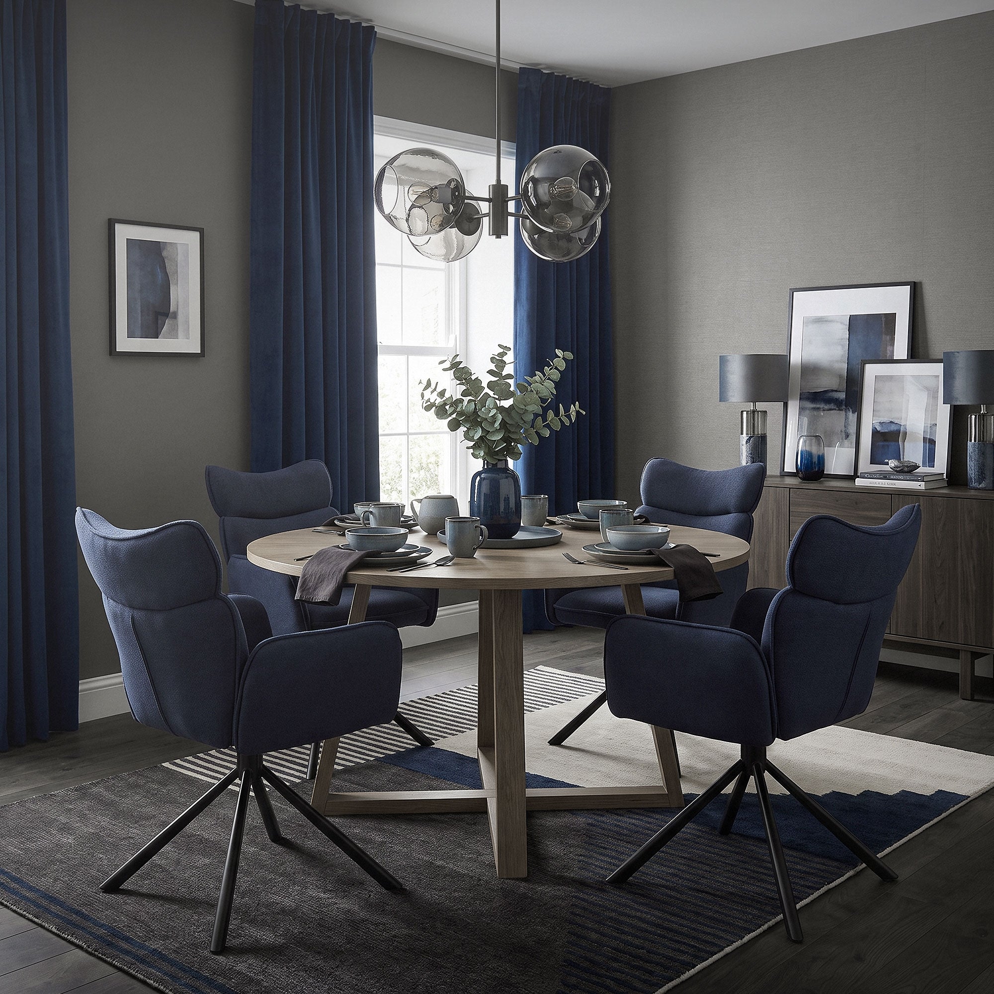 Een eetkamer met een ronde tafel en blauwe stoelen.