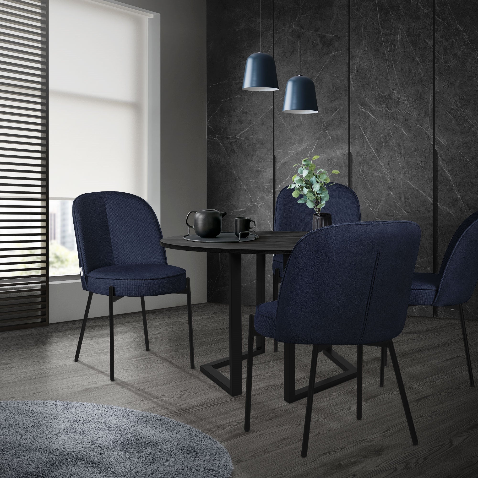 Conjunto de sillas de comedor azul oscuro alrededor de una mesa redonda en un espacio moderno.