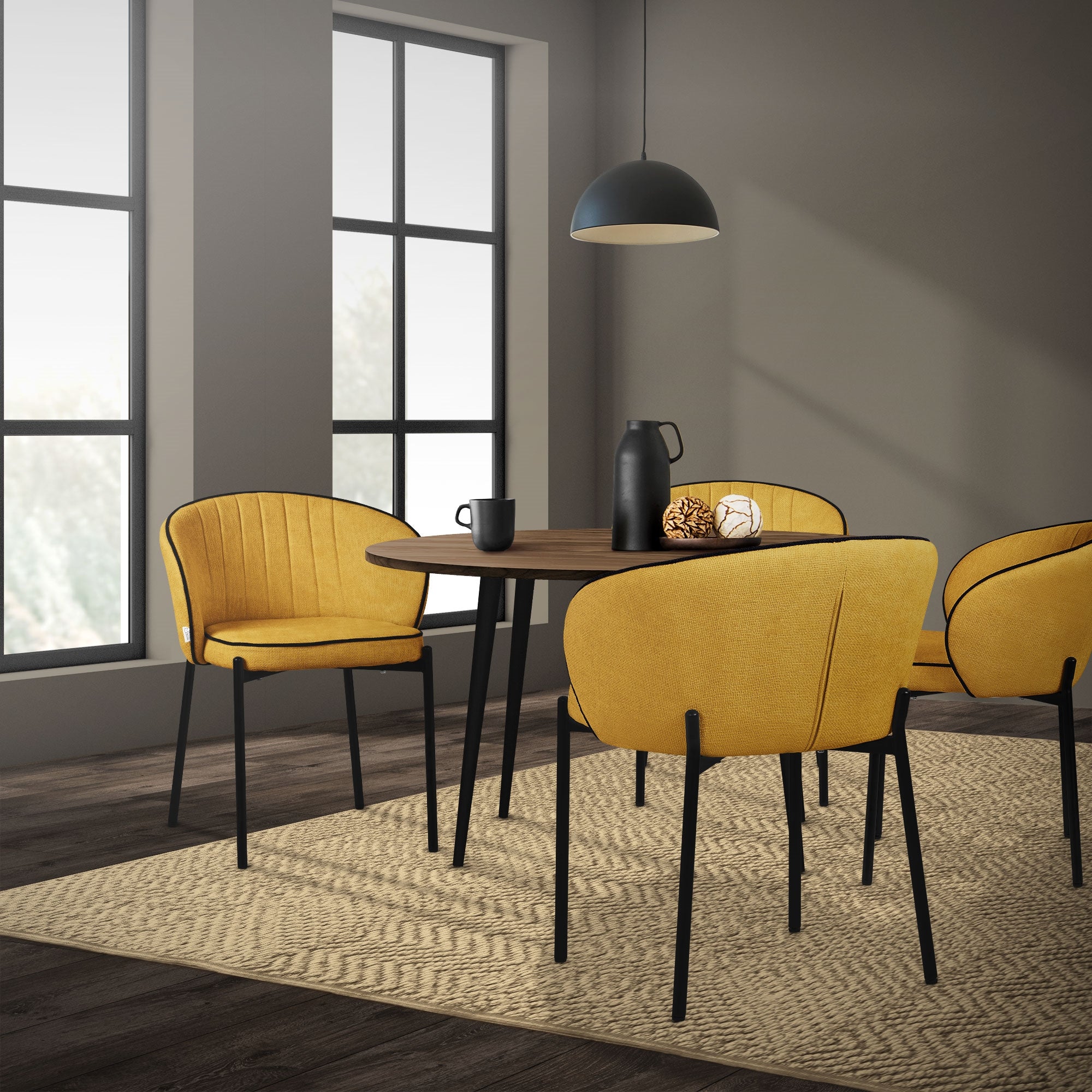 Ein Esszimmer mit einem runden Tisch und vier gelben Stühlen, beleuchtet von einem Pendelleuchte.
