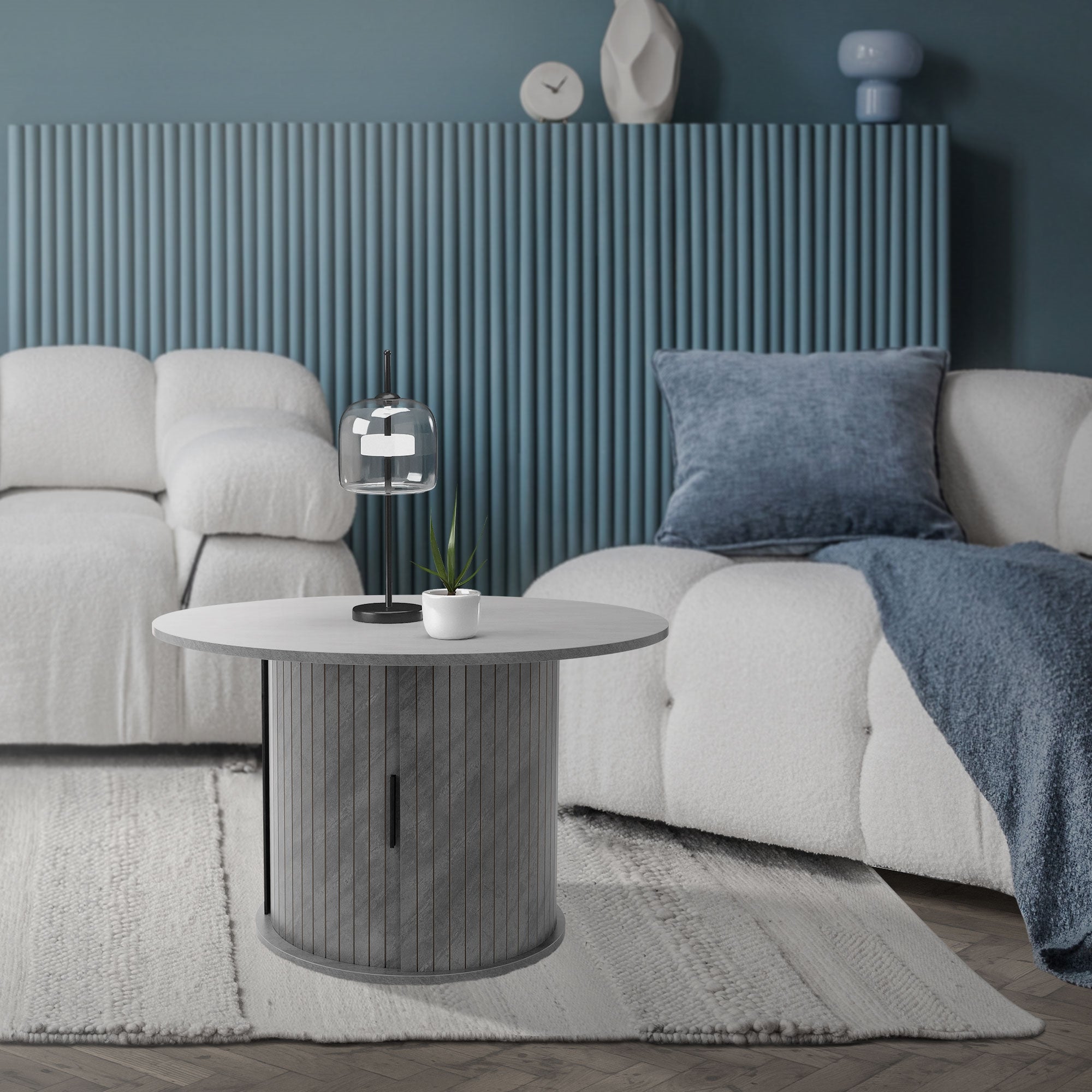 Wohnzimmer mit grauem Tisch, Lampe und beigen Sofas.