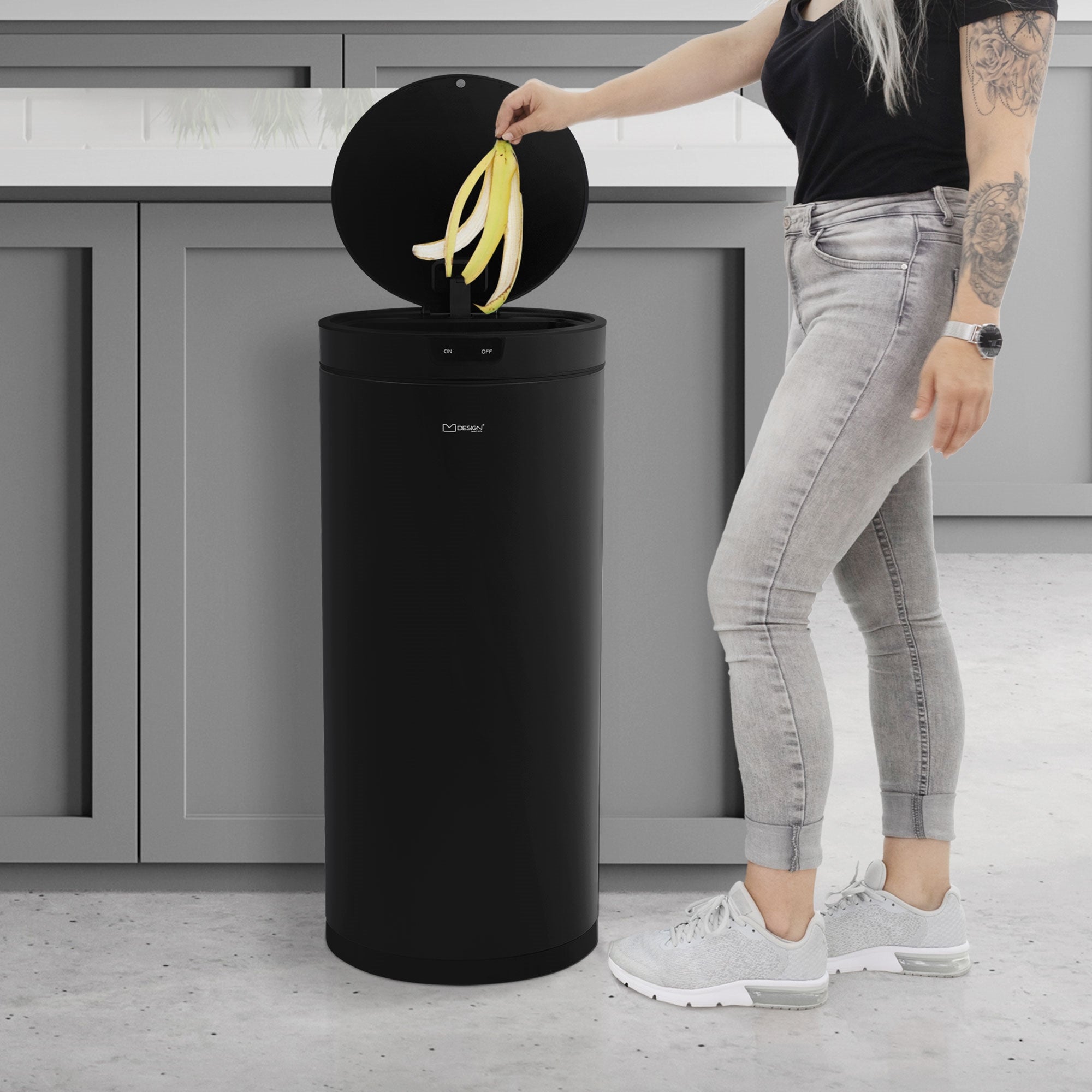 Person med langt hår, der kaster en banan i en sort affaldsspand.