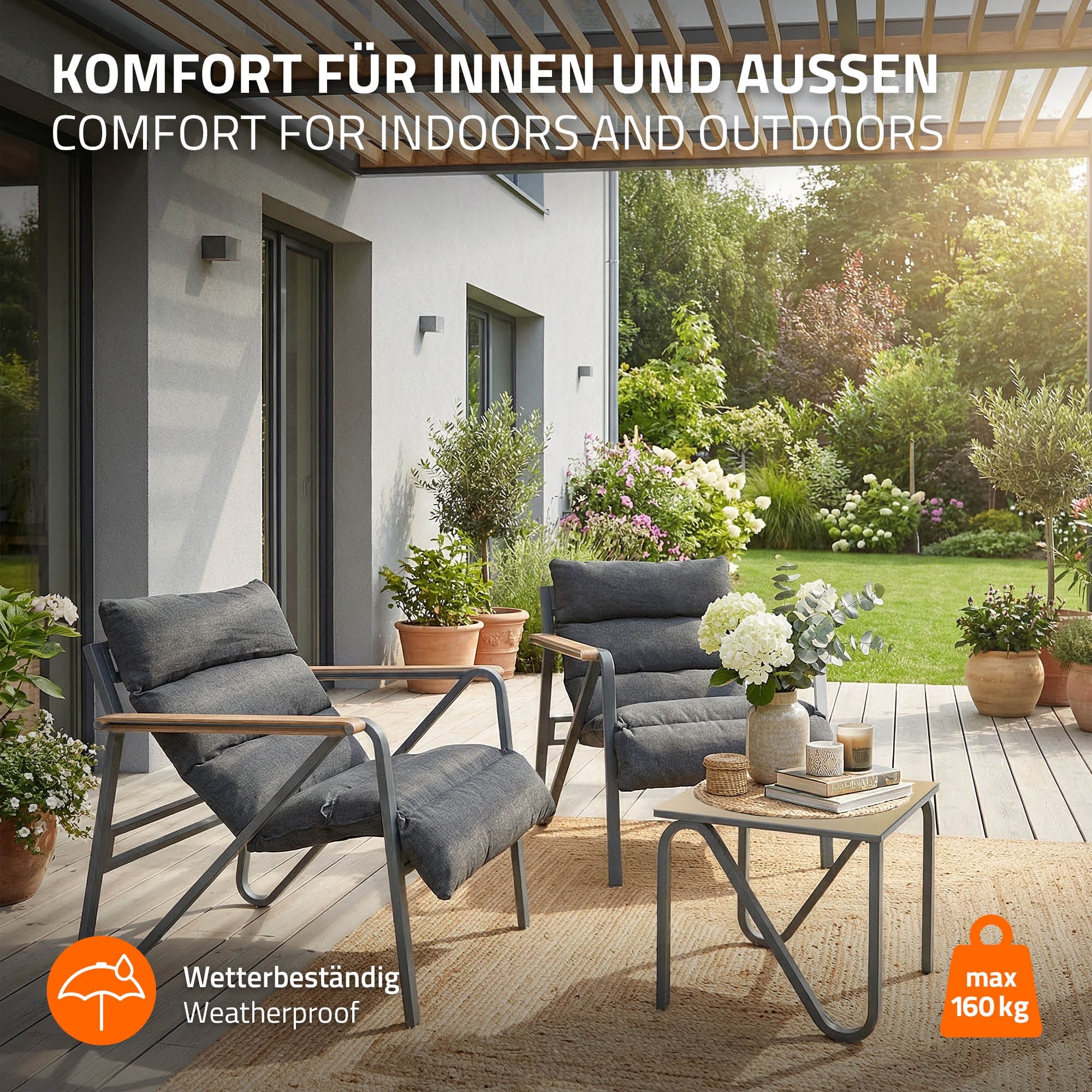 Zwei Stühle und ein Tisch auf einer Terrasse mit Pflanzen im Hintergrund.