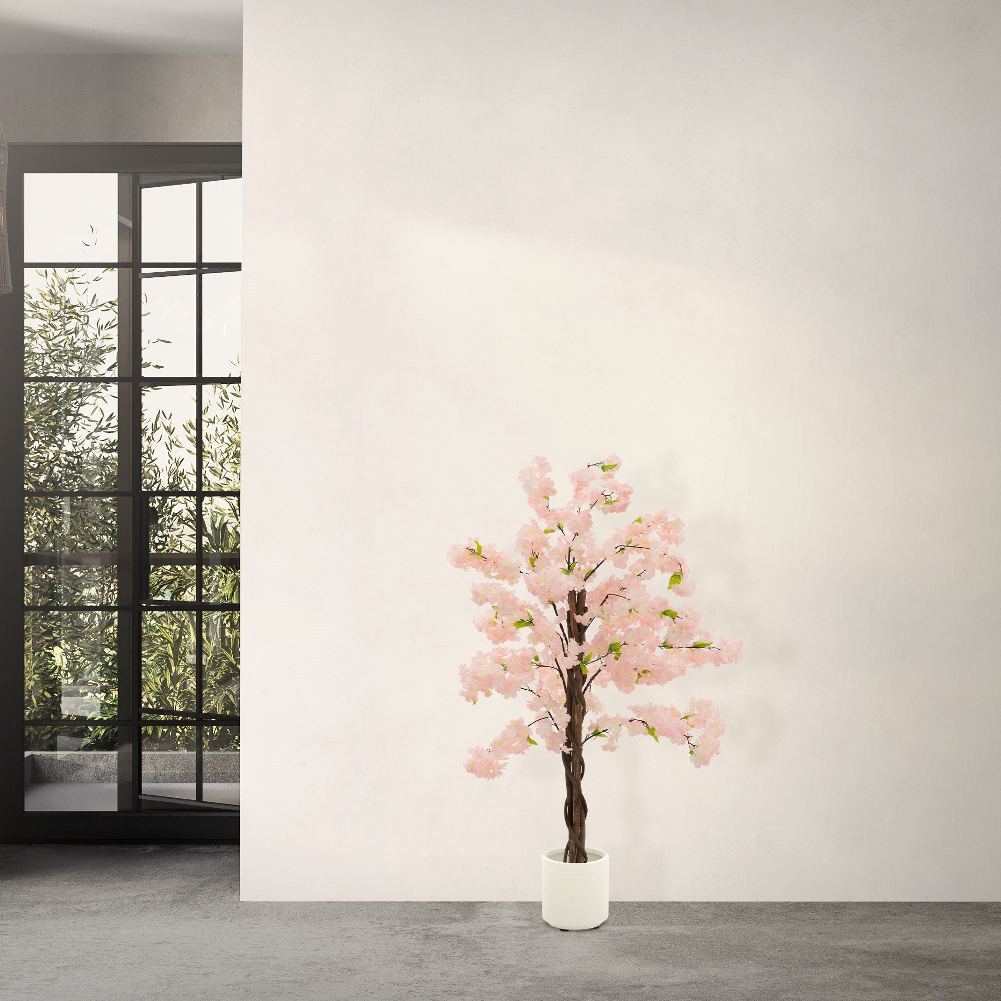 Kunstbaum mit rosa Blüten vor einer Wand und großen Fenstern.