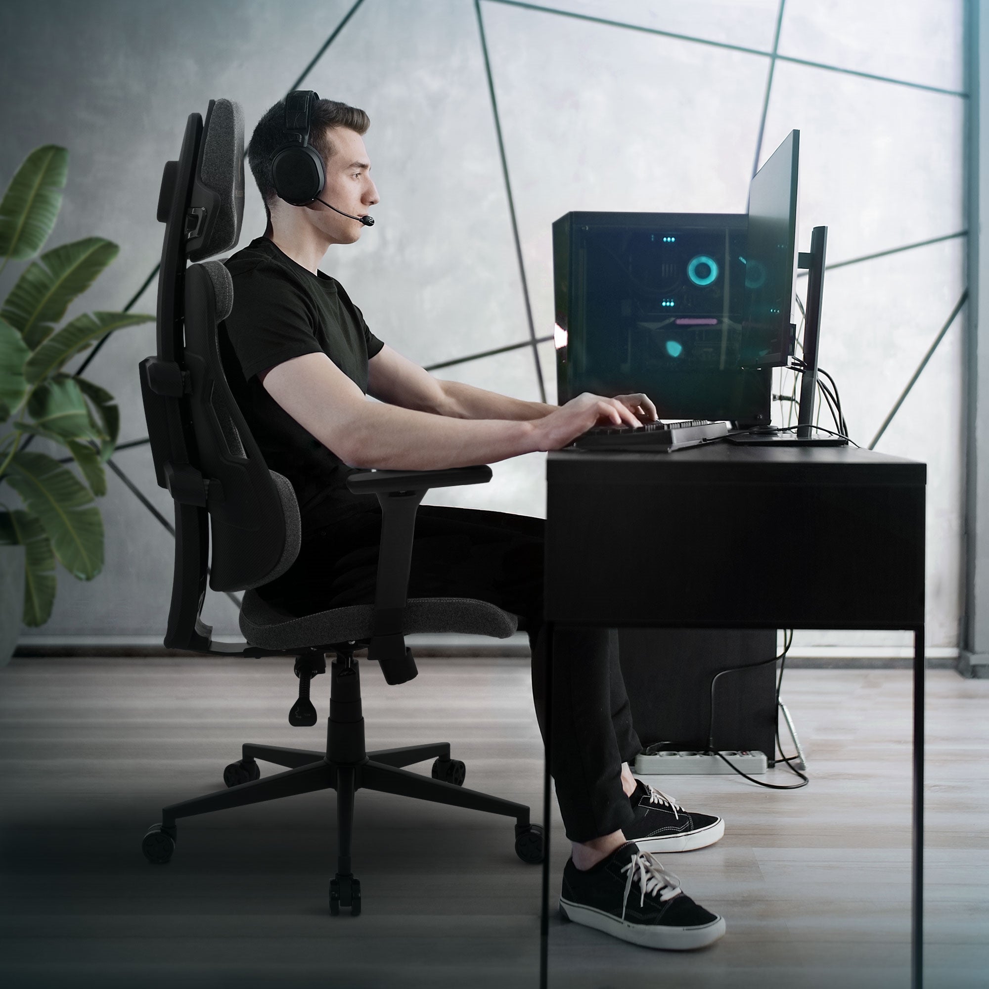 Junger Mann sitzt an einem Schreibtisch mit Computer und Headset.