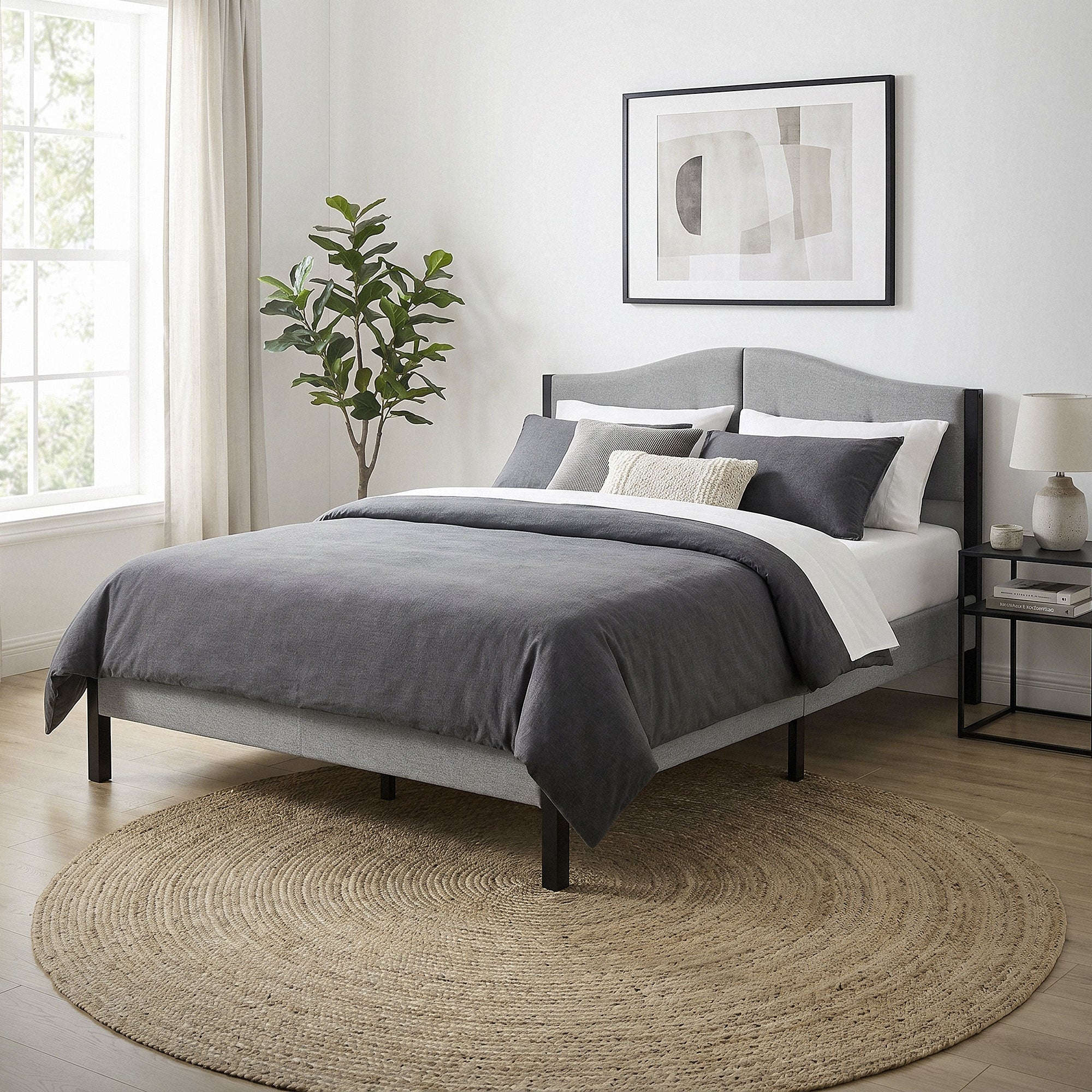 Chambre à coucher avec un lit gris, des coussins et un tapis rond.