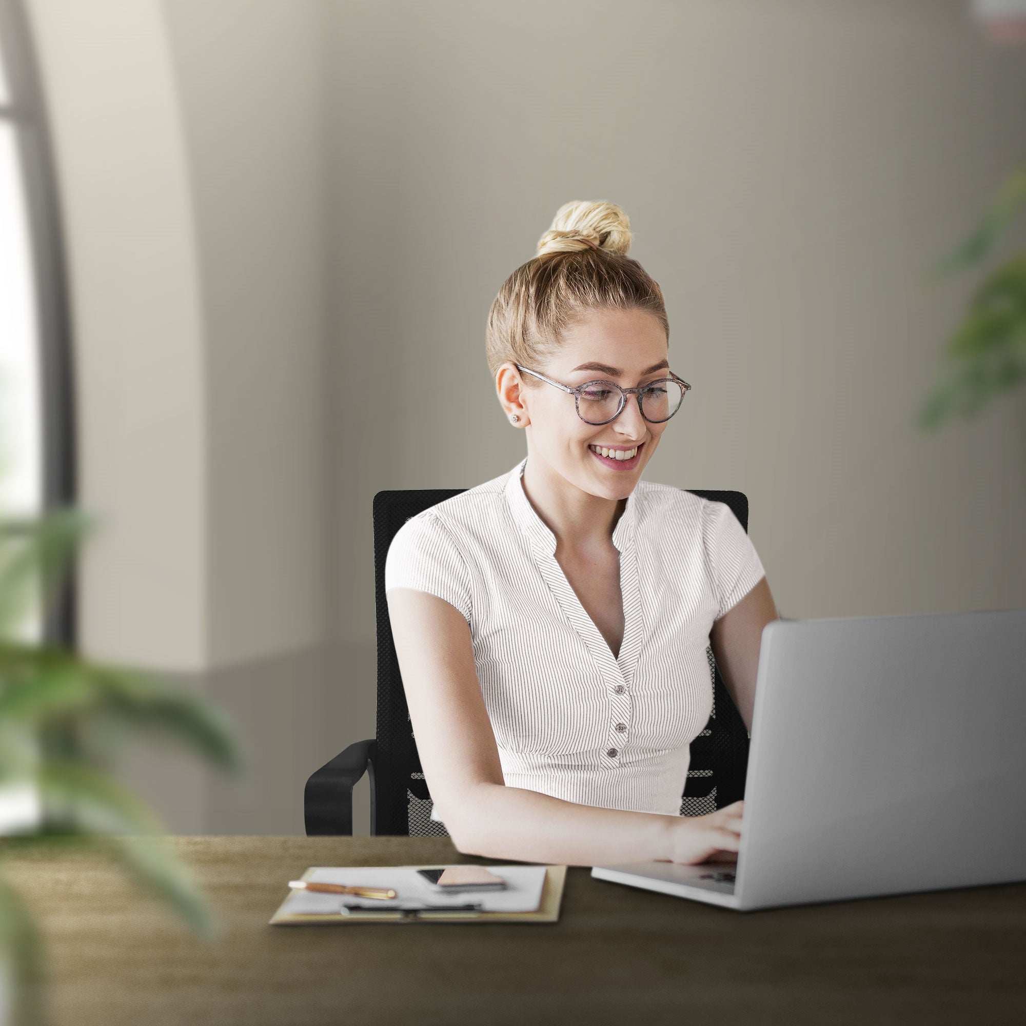 Junge Frau sitzt lächelnd an einem Schreibtisch mit Laptop und Pflanzen.