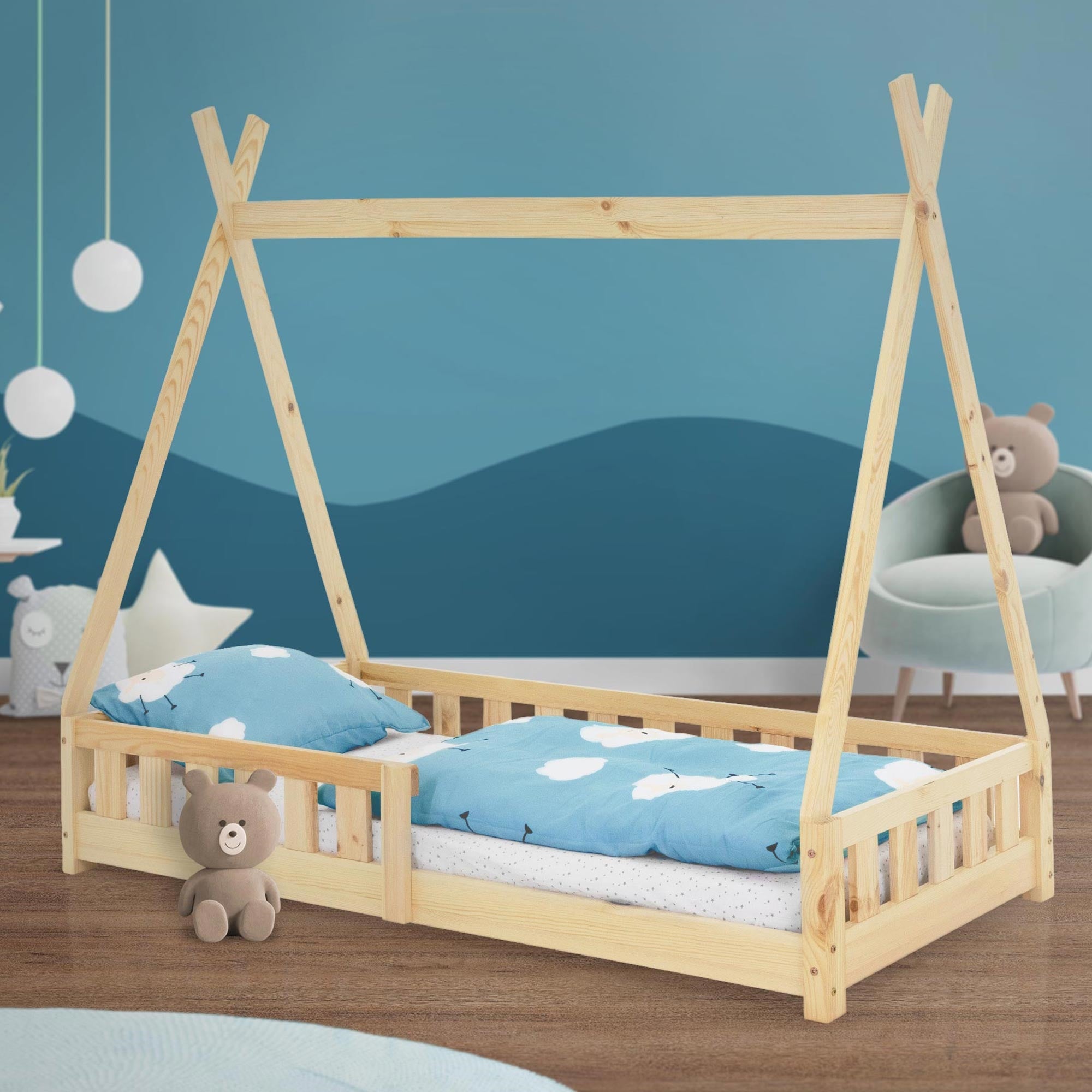 Ein Bett im Zelt-Design mit blauen Bettwäsche und einem Teddybär.