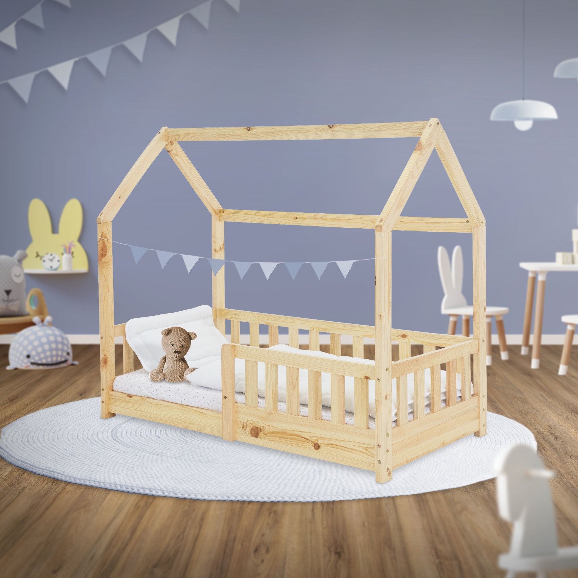 Cama infantil de madera en forma de casa con un osito y almohada sobre un colchón.