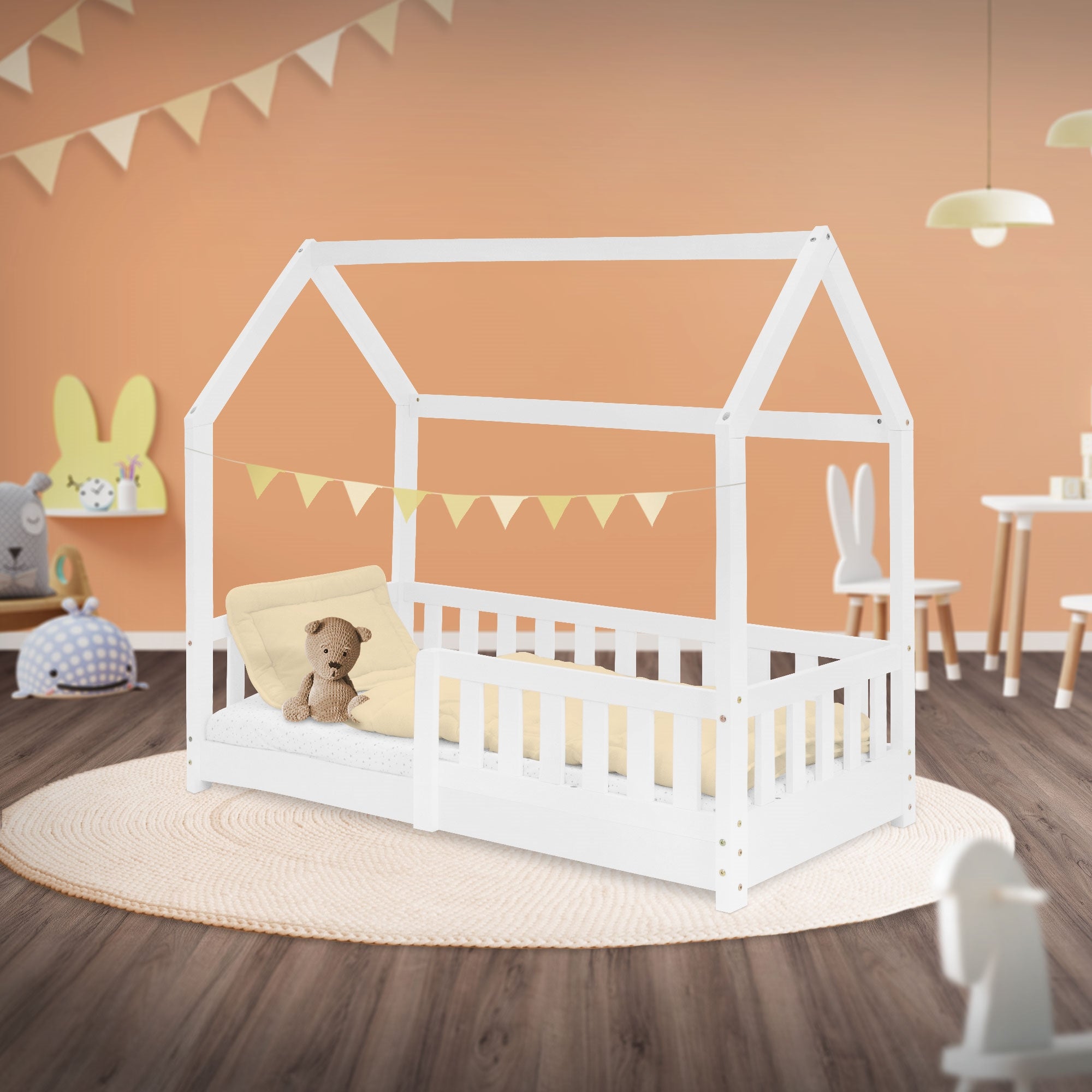 Een wit kinderbed in de kamer met decoratie en een kussen.