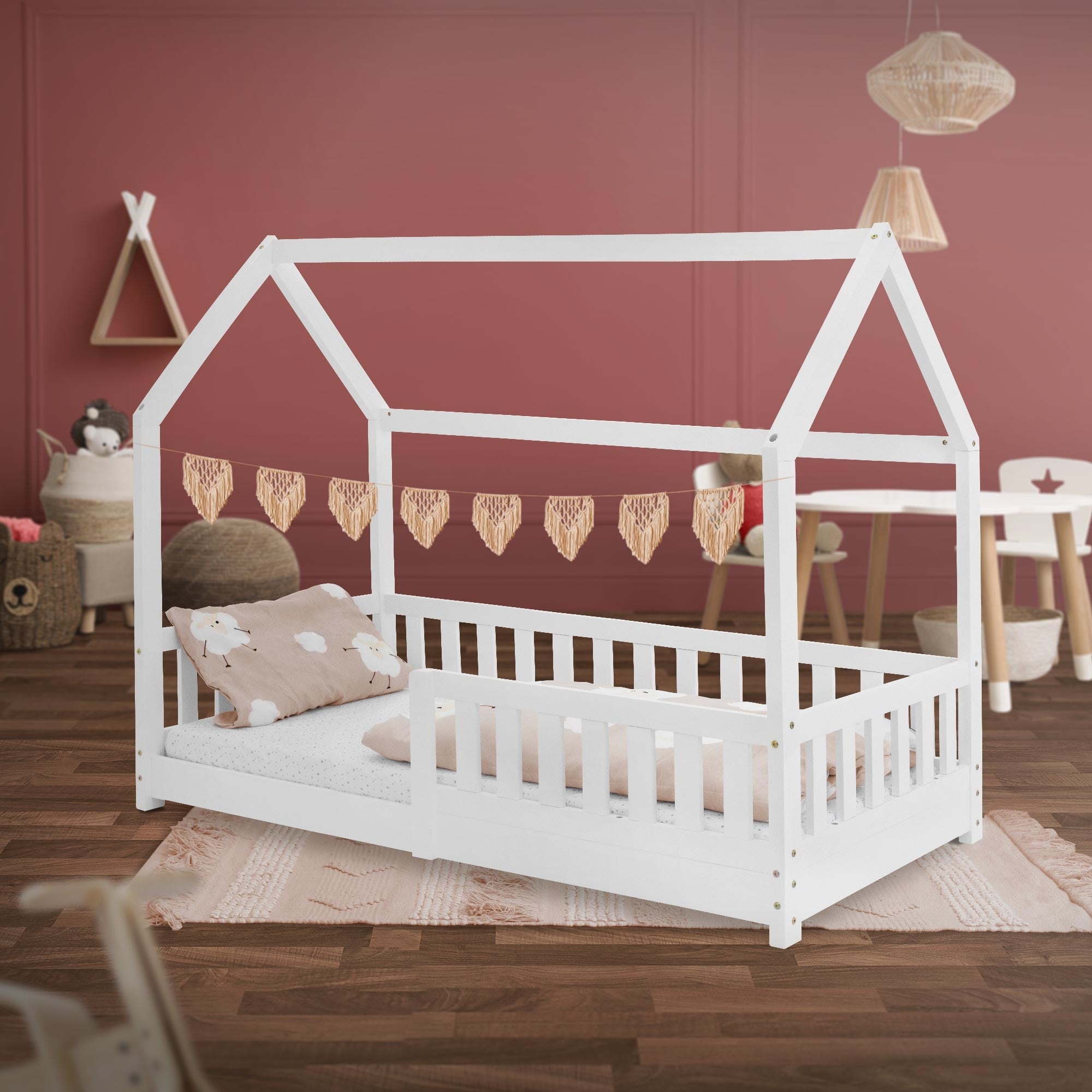 Weißes Kinderbett mit Kissen und Decke, dekoriert mit Herzgirlande.