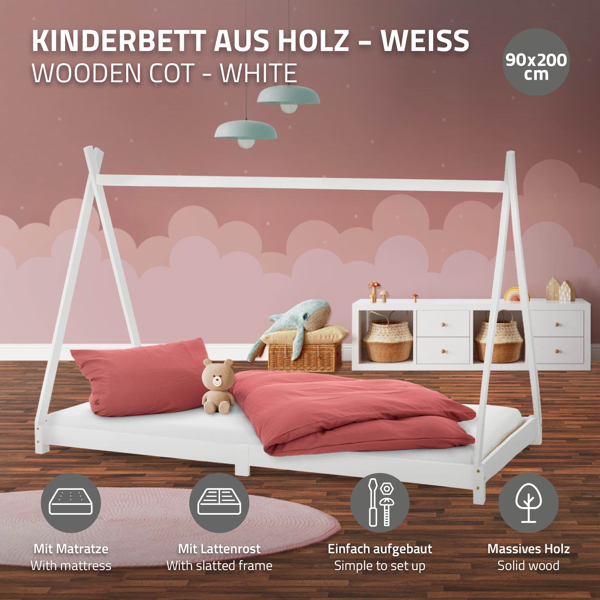 Lit d'enfant en bois blanc avec matelas et coussin dans une pièce.