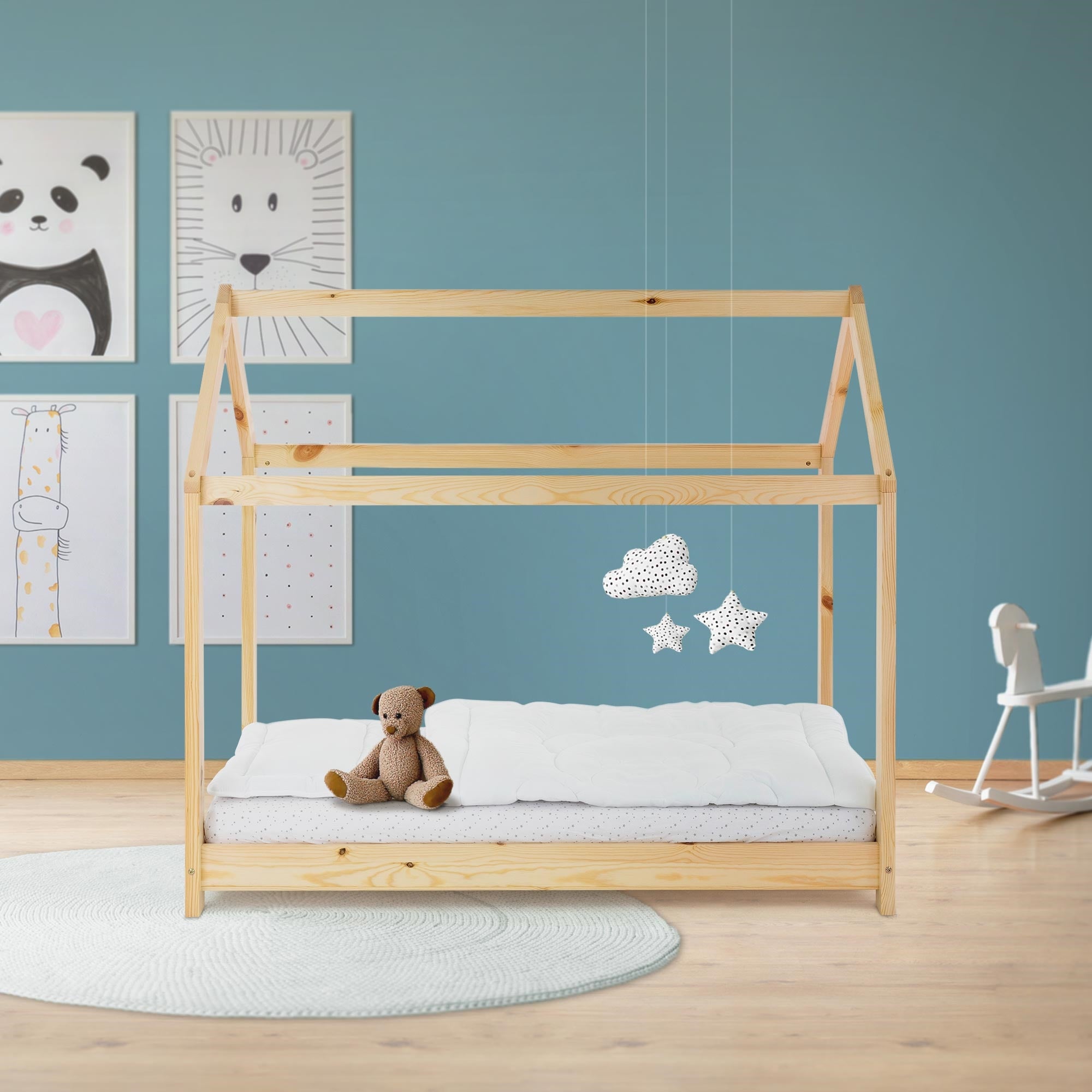 Lit d'enfant en bois avec matelas, ours en peluche et peintures murales colorées.