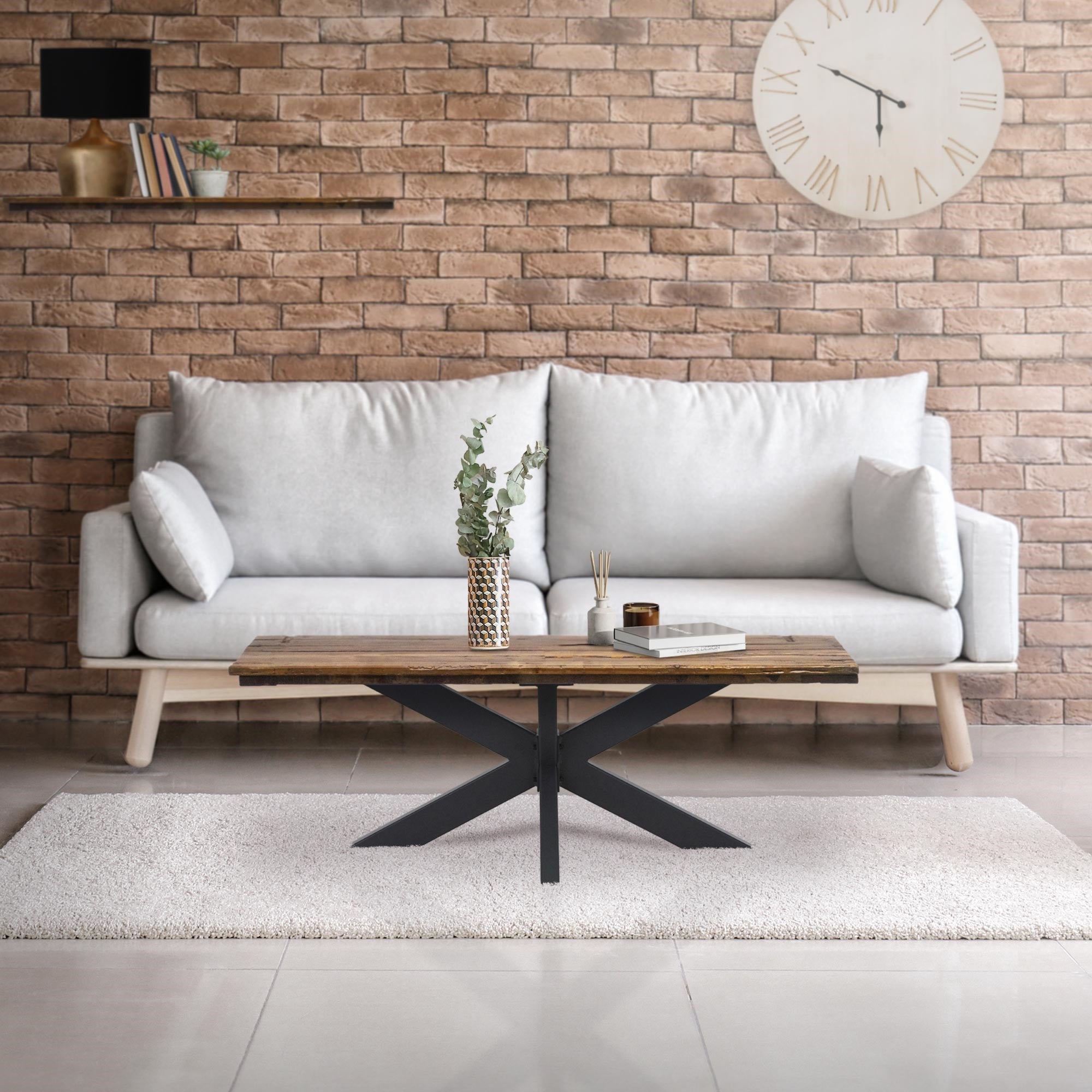 Wohnzimmer mit grauem Sofa, Holztisch und Ziegelsteinwand.