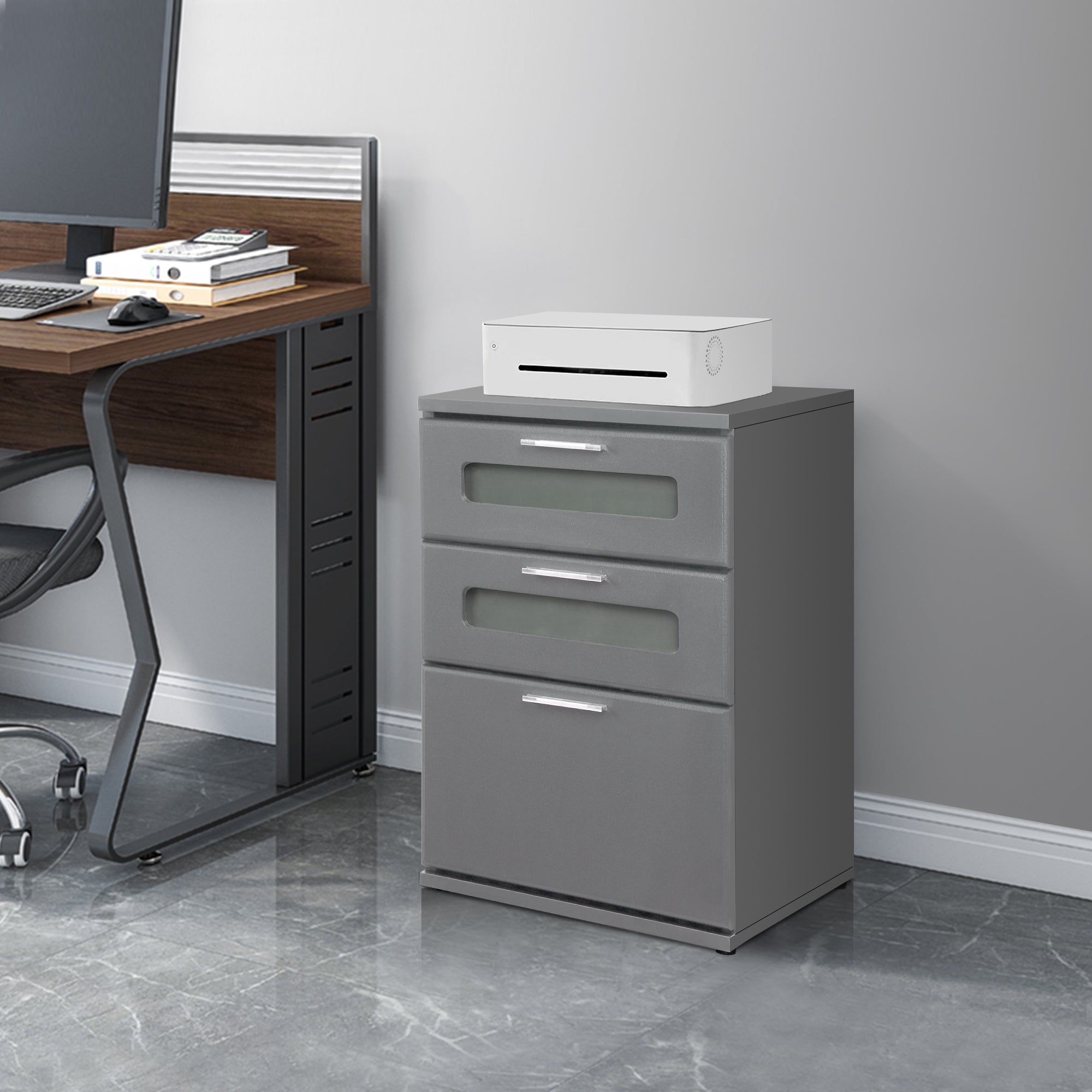 Armadio grigio con tre cassetti e un dispositivo bianco sulla parte superiore.