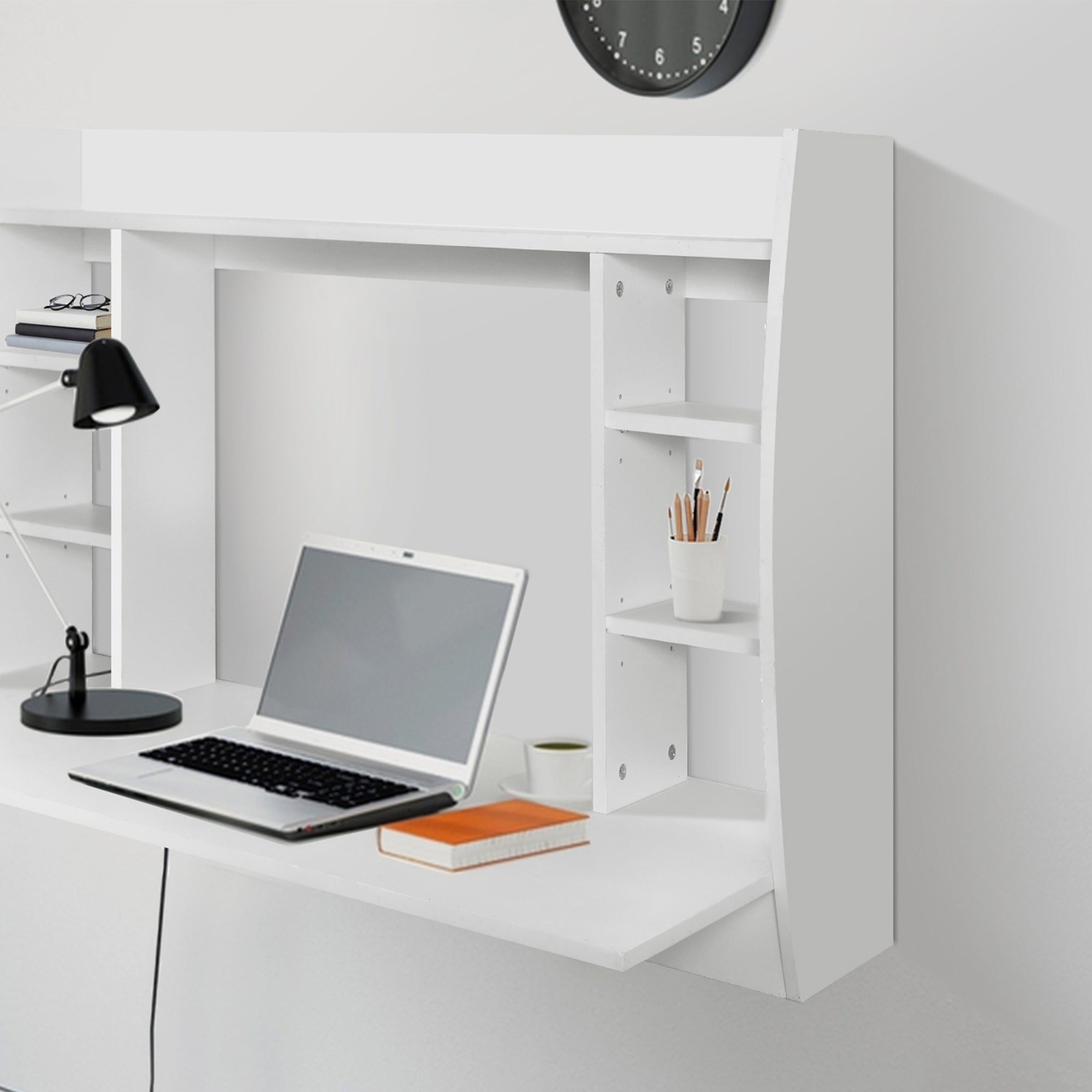 Weißer Schreibtisch mit Laptop, Lampe und Regalen.