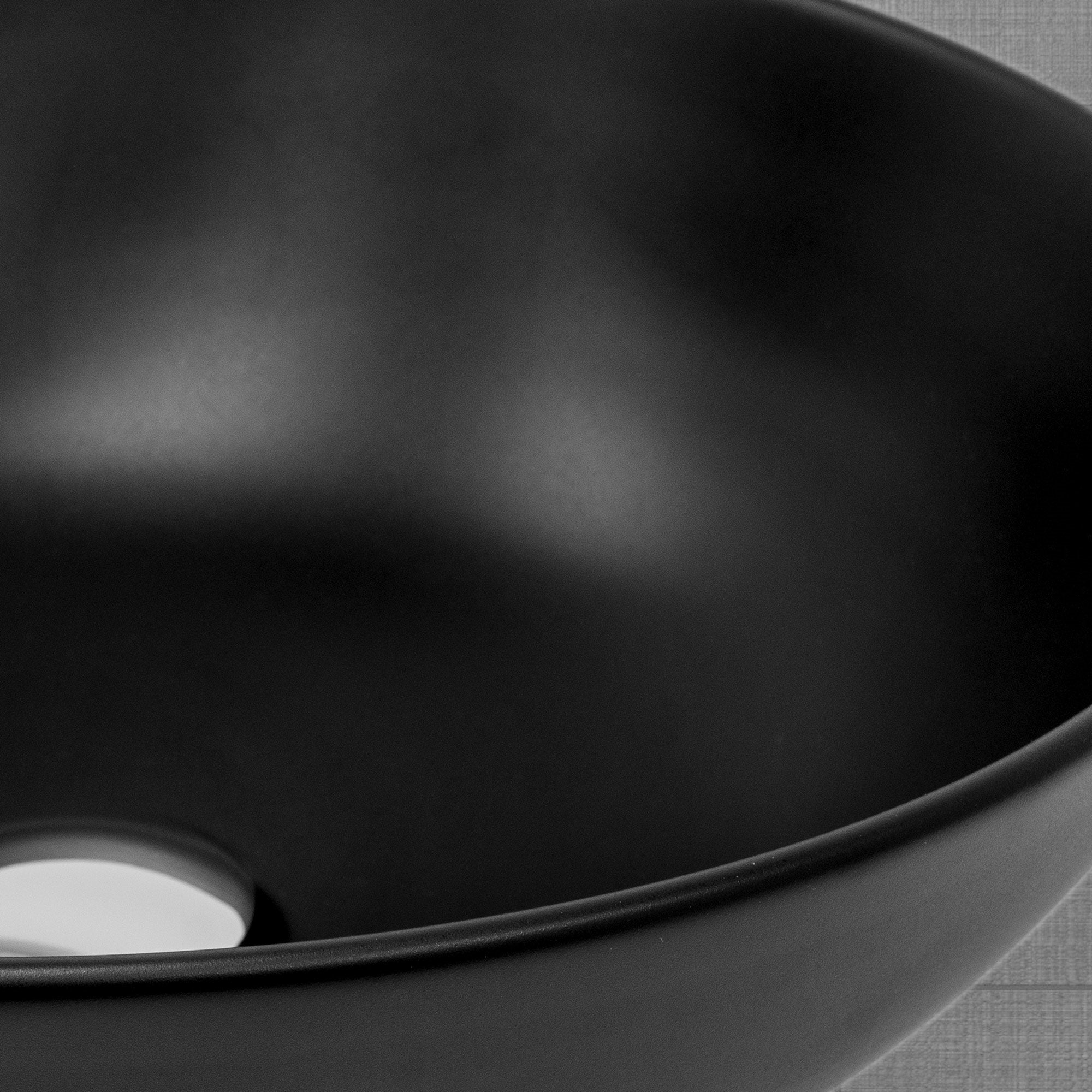 Schwarzes, rundes Waschbecken mit Abflussöffnung.