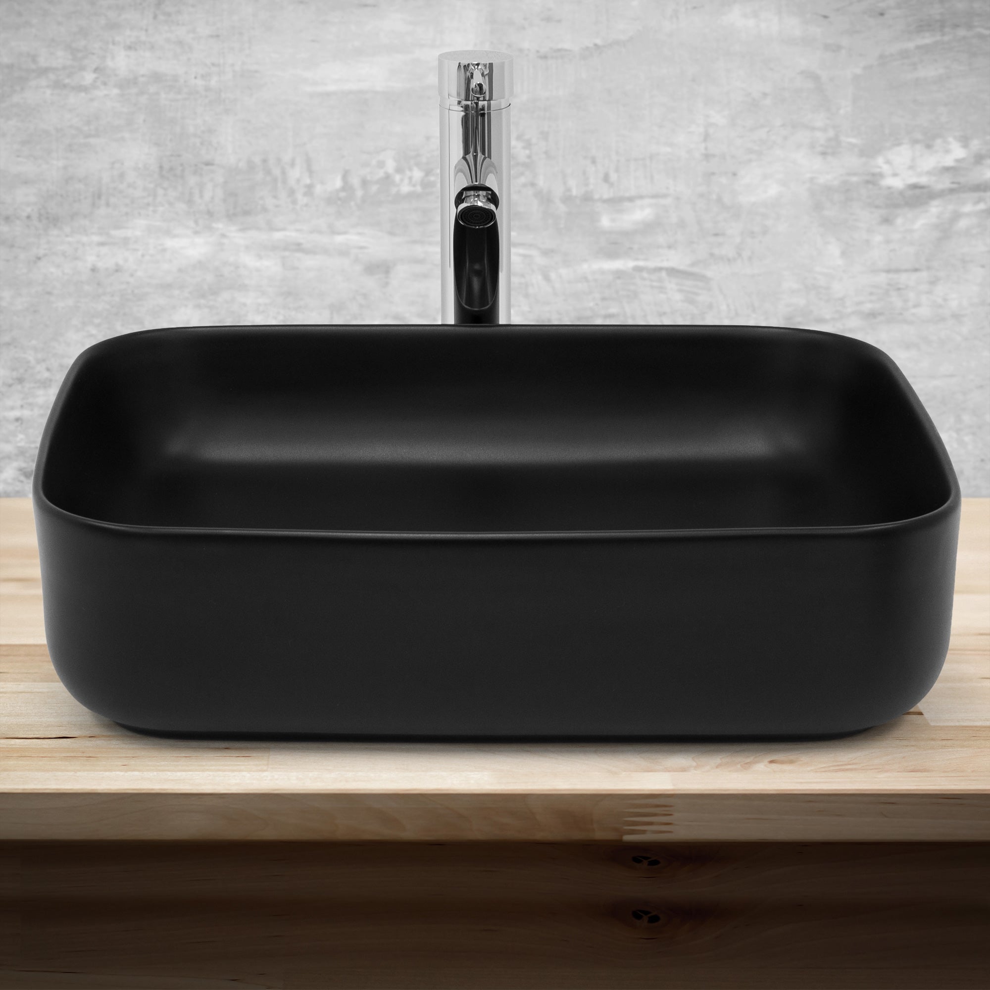 Black rectangular washbasin with faucet on a wooden surface.