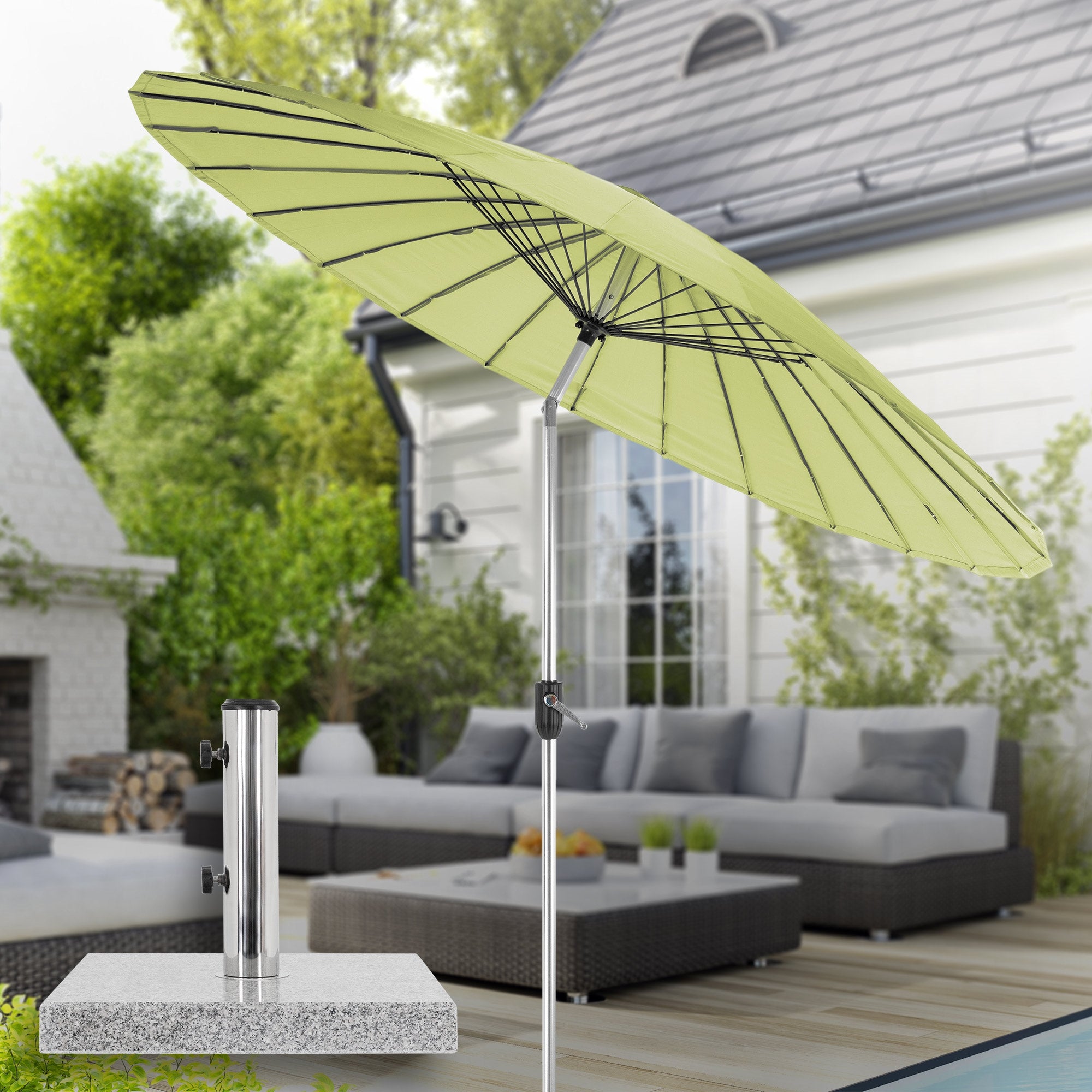 Parasol ouvert en vert, sur une terrasse avec des meubles.