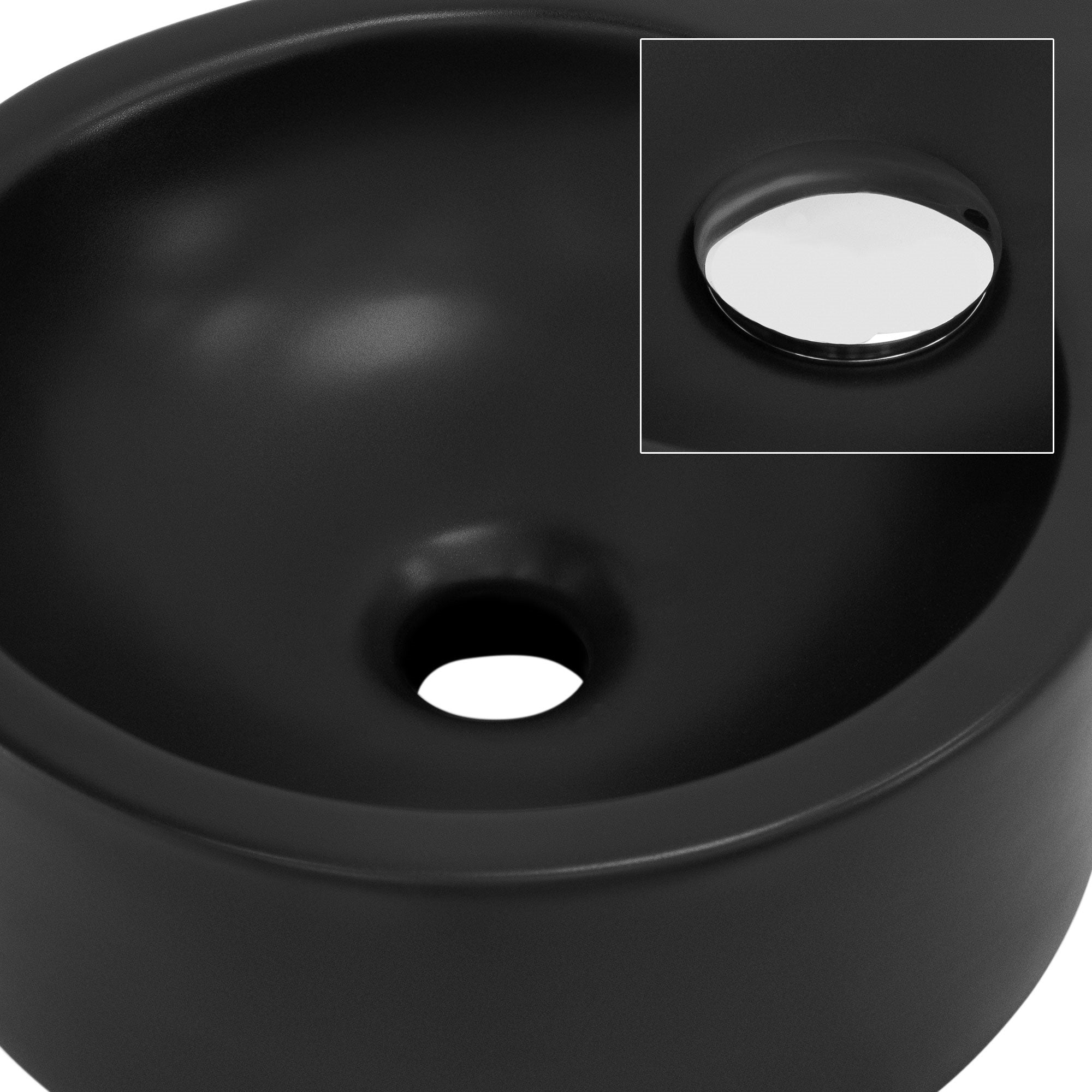 Lavabo nero con apertura di scarico e specchio sullo sfondo.