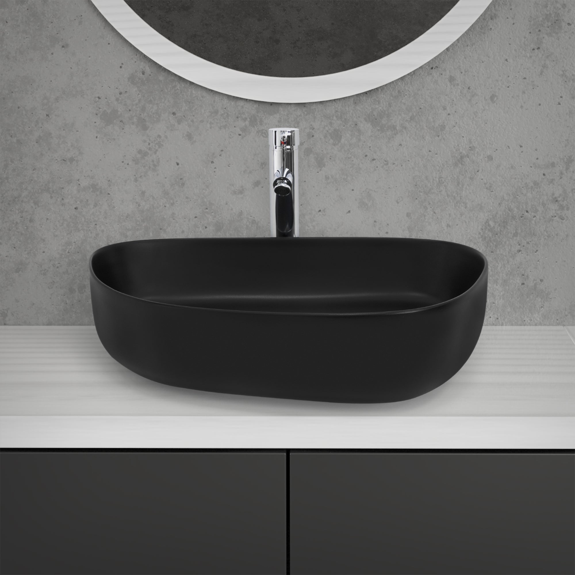 Un lavabo nero su un tavolo bianco davanti a una parete grigia.