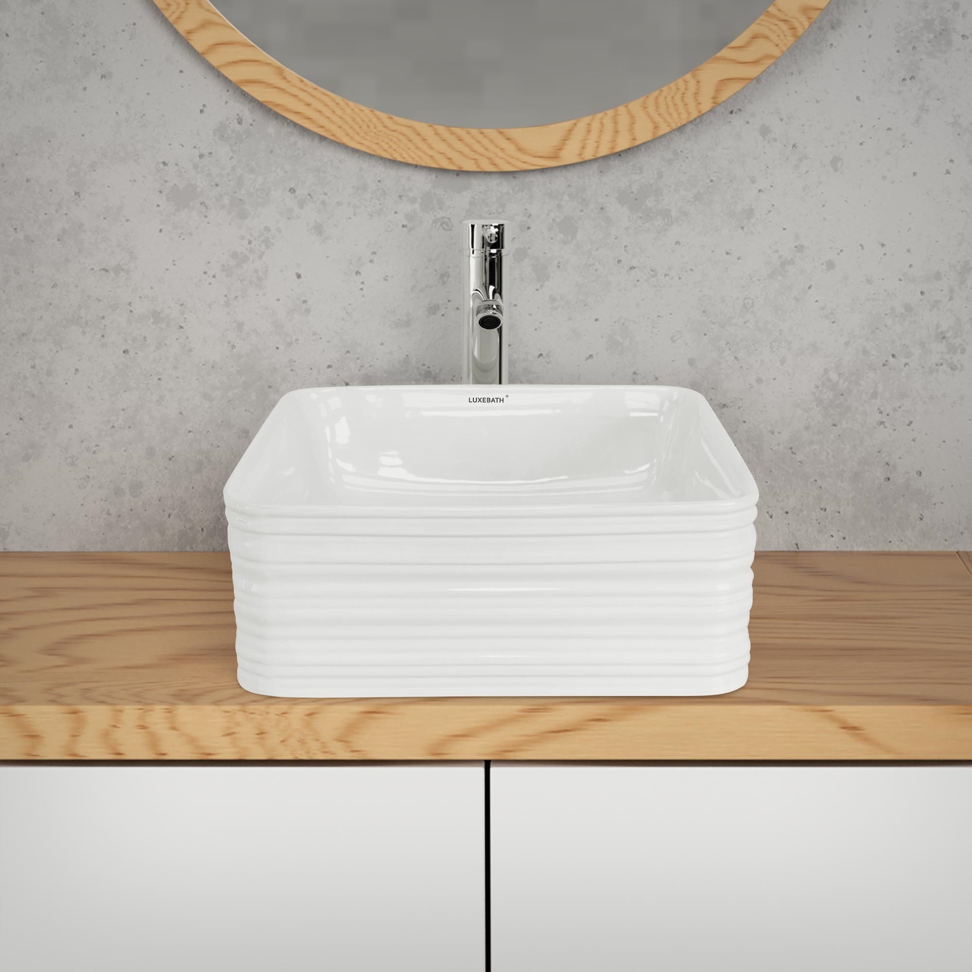 Weißes Waschbecken auf einem Holzwaschtisch mit Spiegel im Hintergrund.