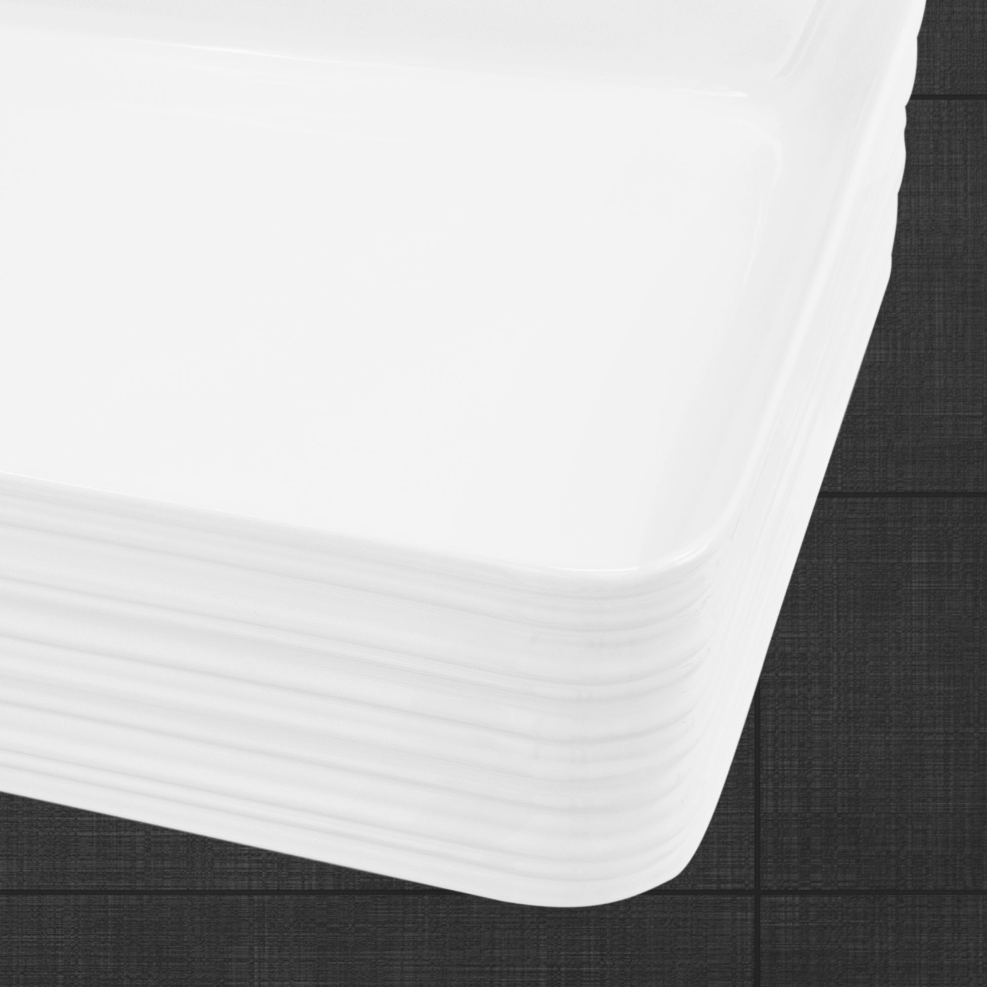 Empilement d'assiettes blanches et rectangulaires sur fond sombre.