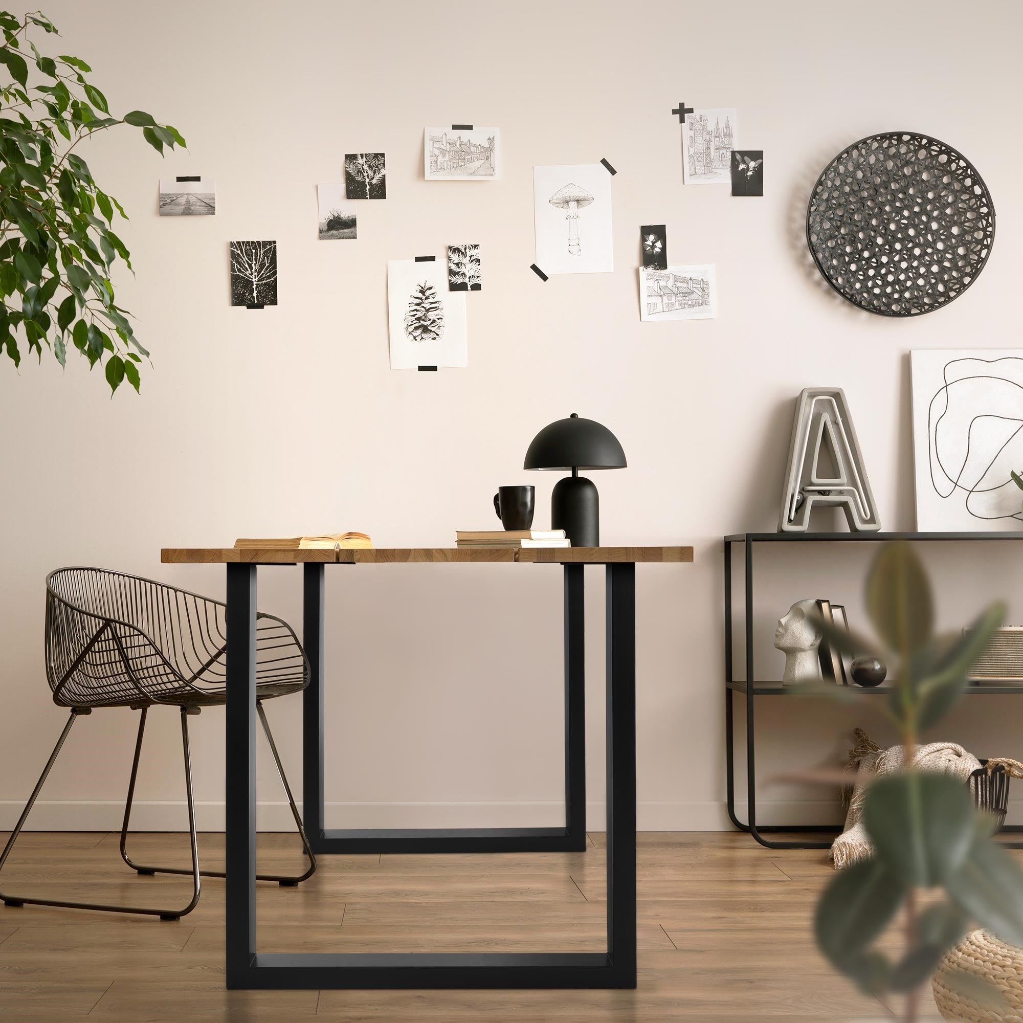 Una mesa moderna con una lámpara, silla y cuadros en la pared.