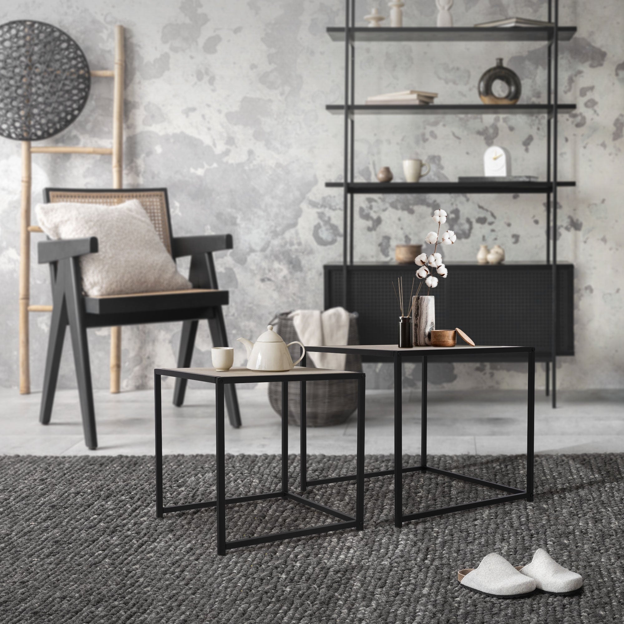 Tables noires avec une théière et des fleurs sur un tapis.