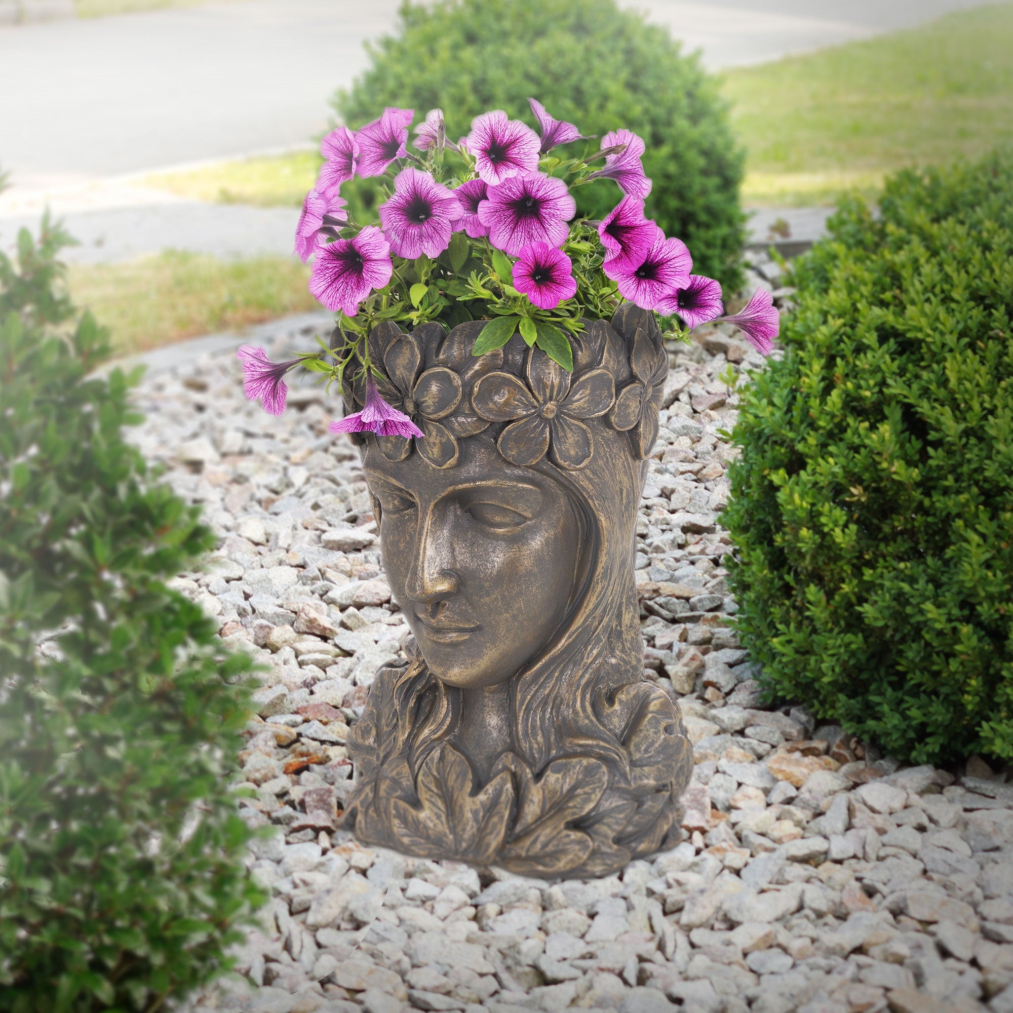 Buddha-hoved plantekrukke i haven med blomstrende petunier.