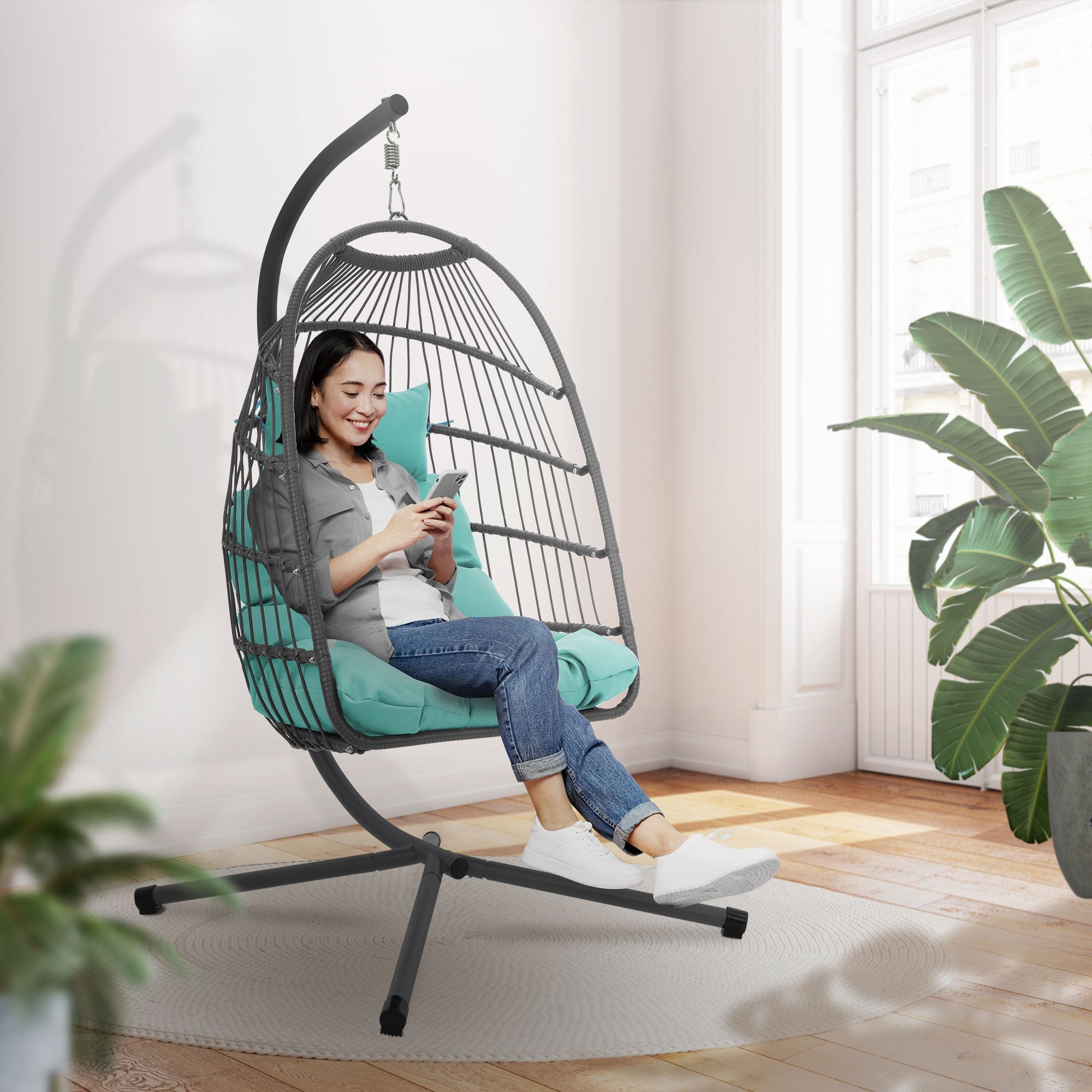Mujer sentada en un sillón colgante usando un smartphone.