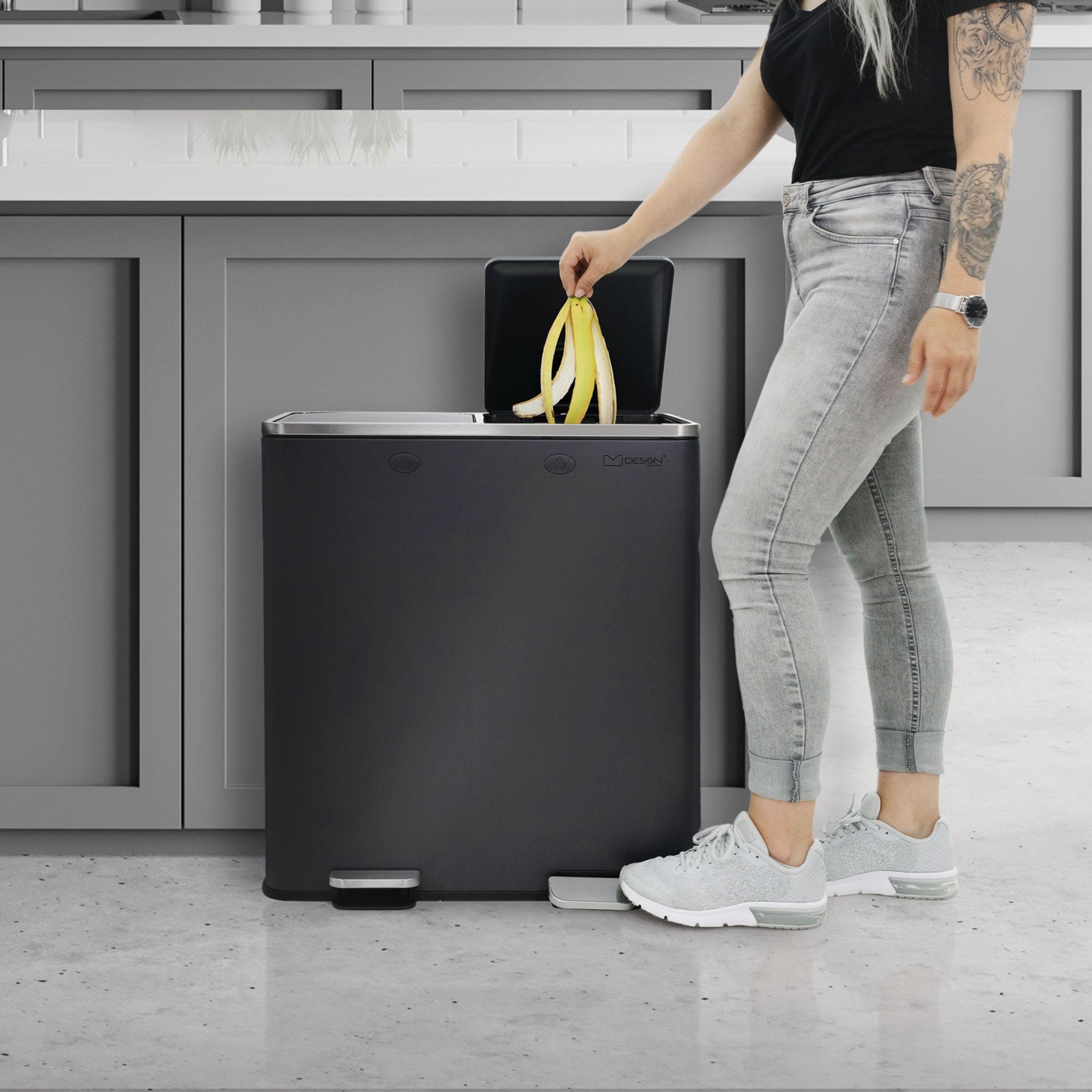 Une personne aux cheveux longs jette une banane dans un conteneur à déchets.