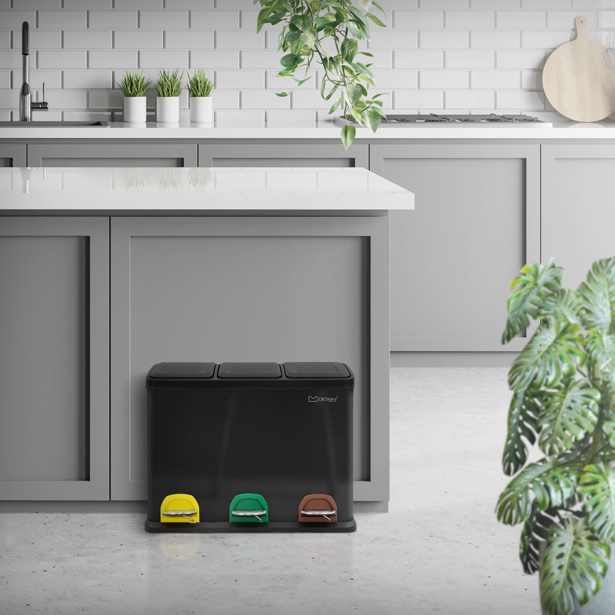 Mülltrennsystem mit drei farbigen Pedalen vor einer modernen Küchenzeile.