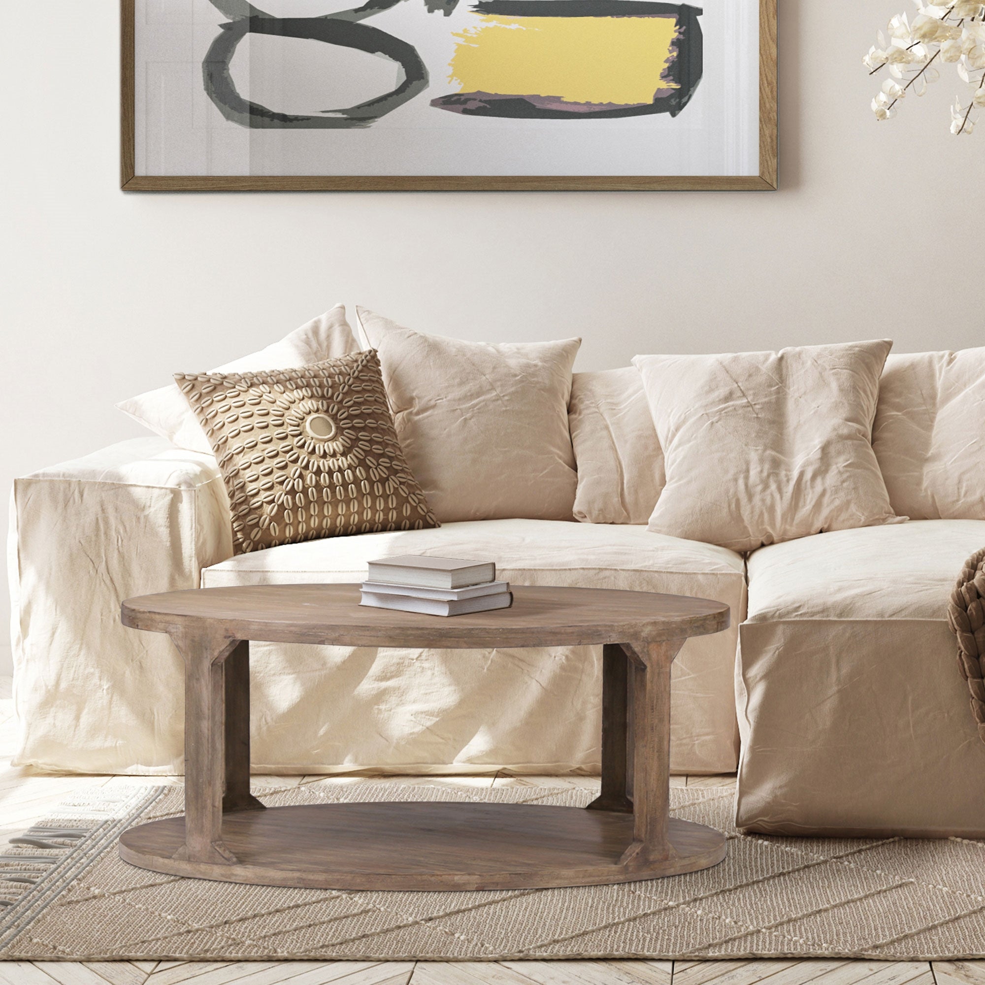 Soggiorno con divano beige, cuscini e un tavolo rotondo in legno.