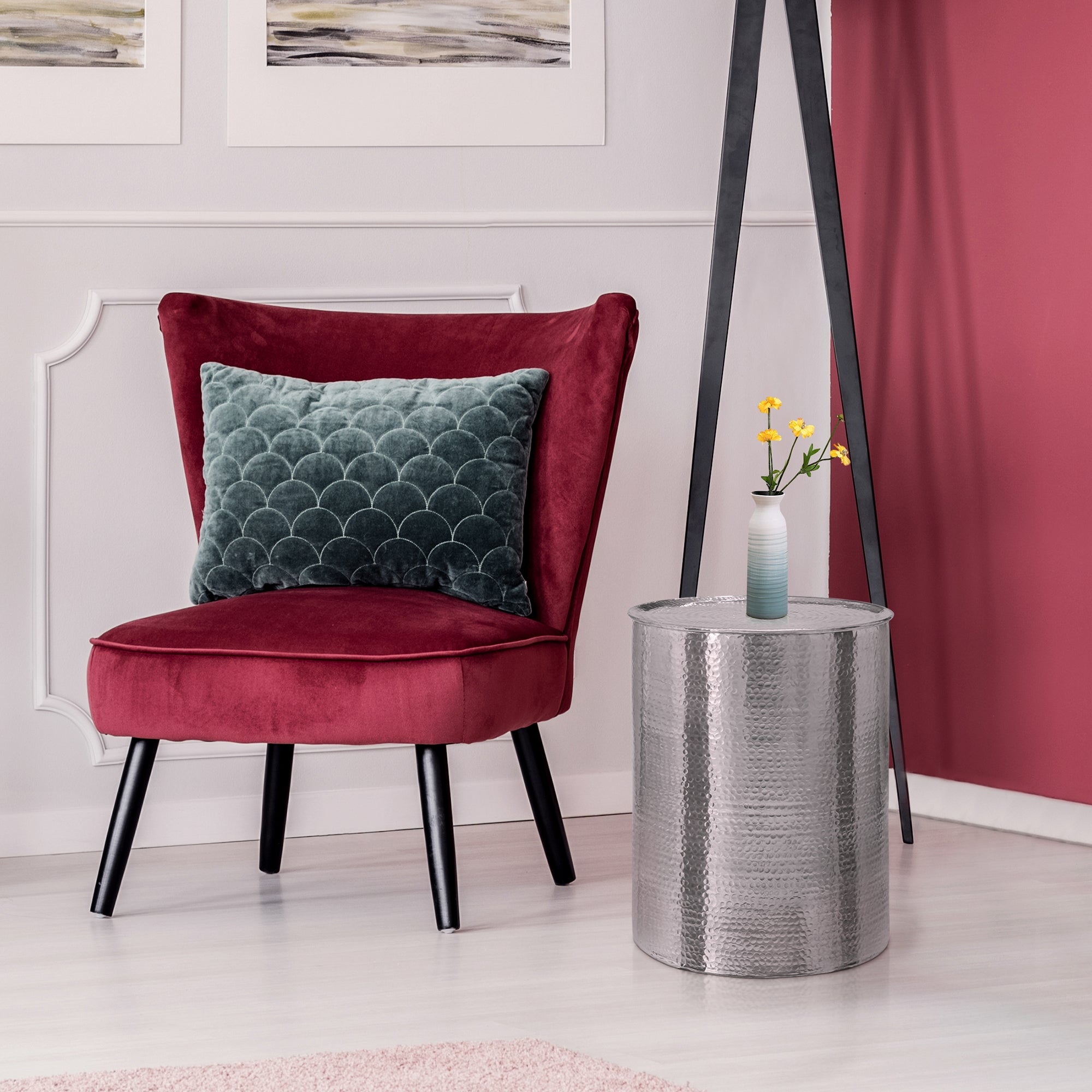 Poltrona rossa con cuscino e tavolino in argento in un ambiente moderno.